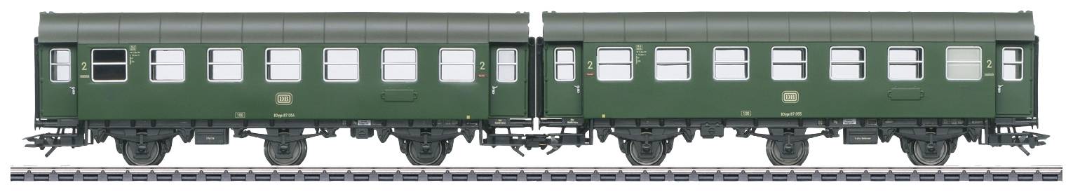 Two green historical railway carriages stand on the same track. Rows of windows are visible. They evoke memories of past passenger trains.