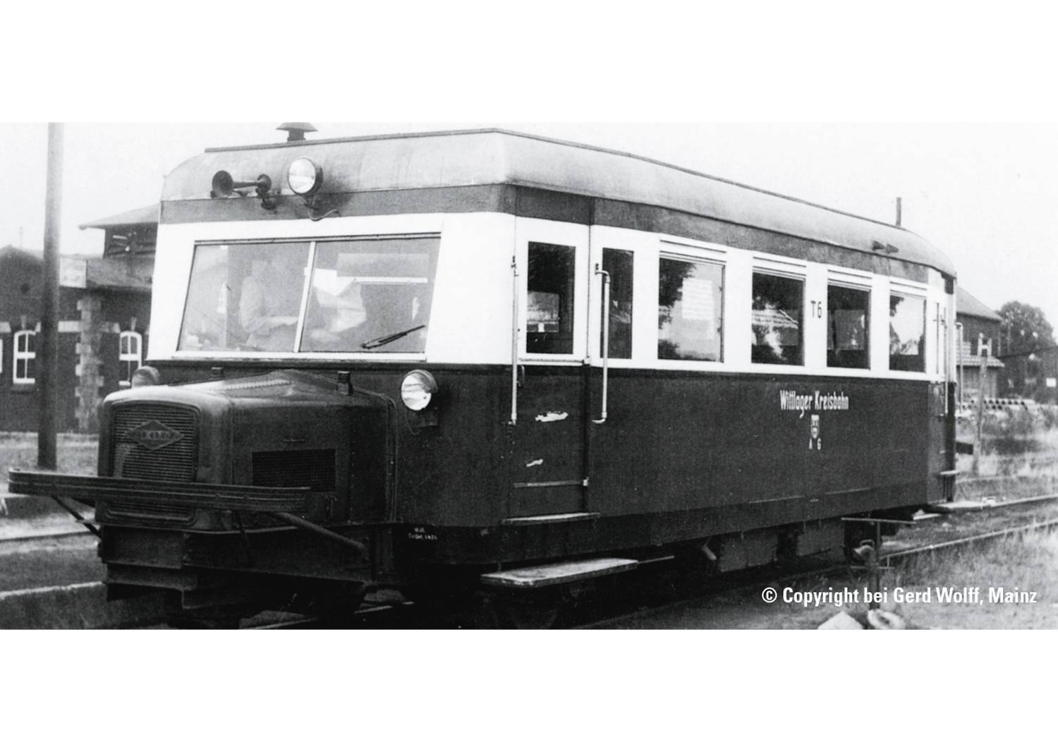 An antiquated railcar stands on a track. Inscription: 'Sülzener Railcar'. Surroundings: rural, with buildings in the background.