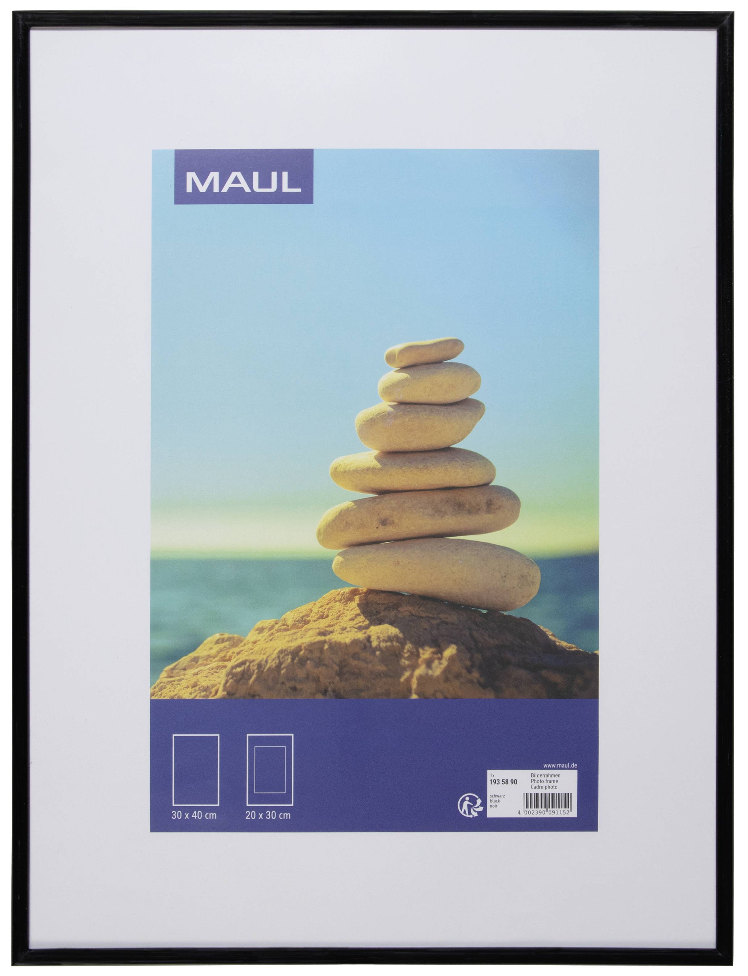 A stack of pebbles balances on a rock against a blue sky with a sea backdrop.