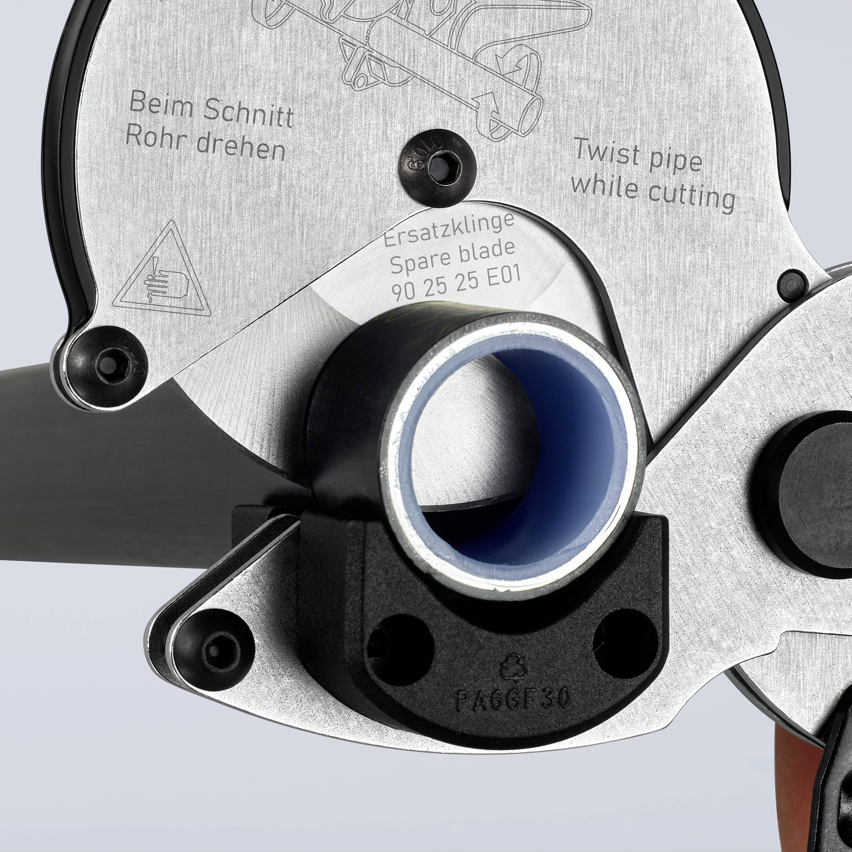 Close-up of a pipe cutter with labels in English and German. Shows replacement blade and instructions for pipe rotation.