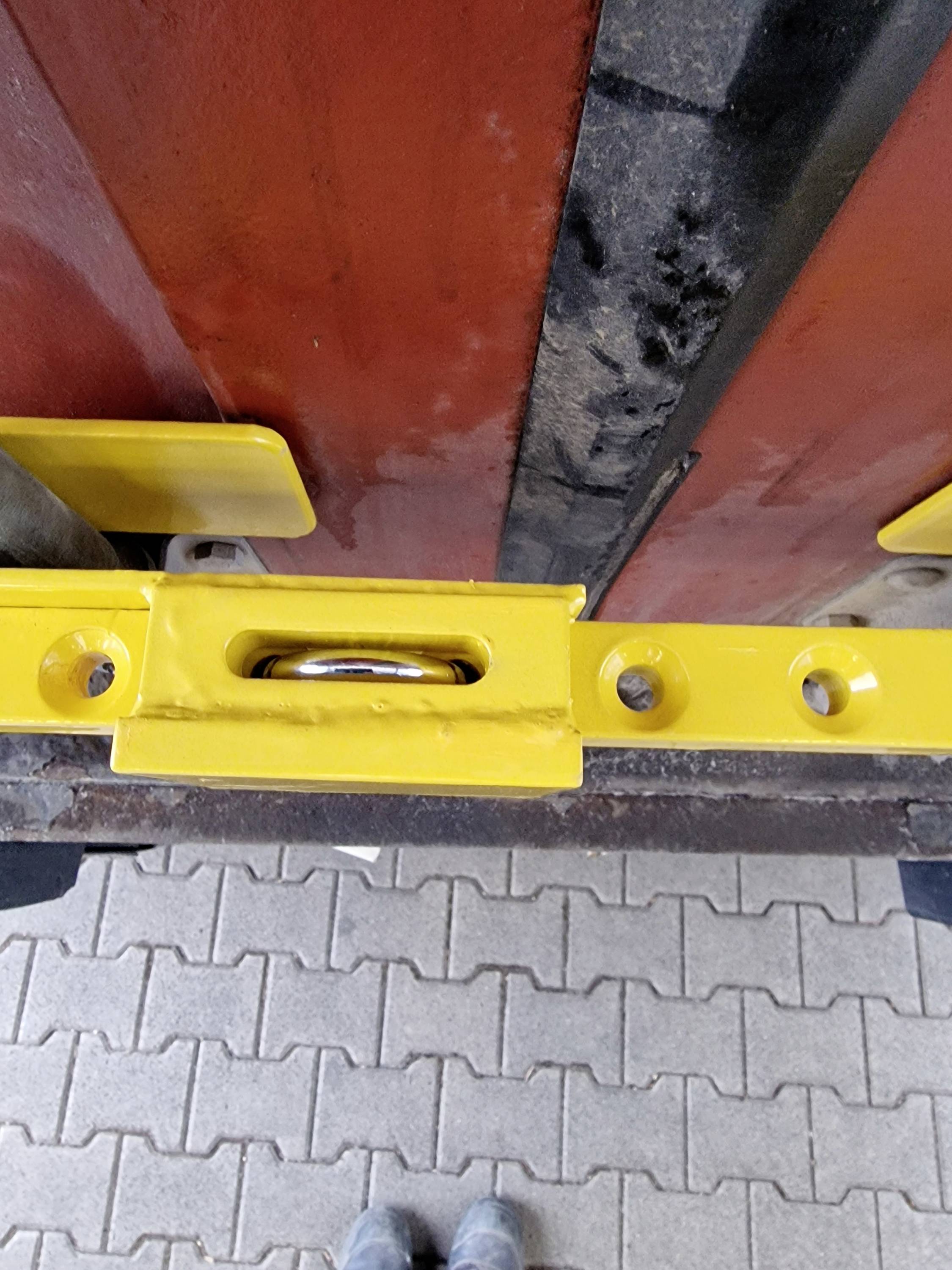 Yellow spirit level on red wood and cement floor, indicating levelling during construction or installation.
