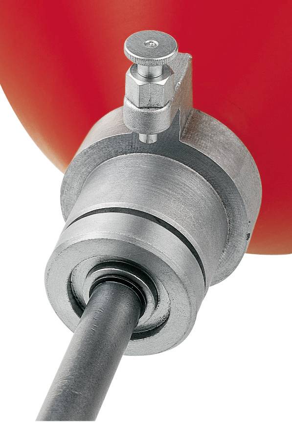 A silver metal valve with a black pipe is mounted against a red background.
