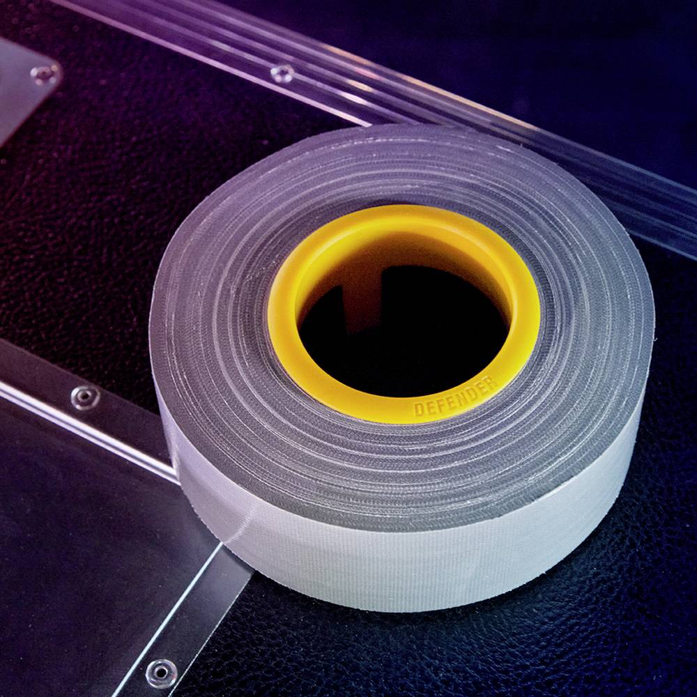 Roll of grey adhesive tape with a yellow inner ring on a dark background, illuminated by blue and pink light.