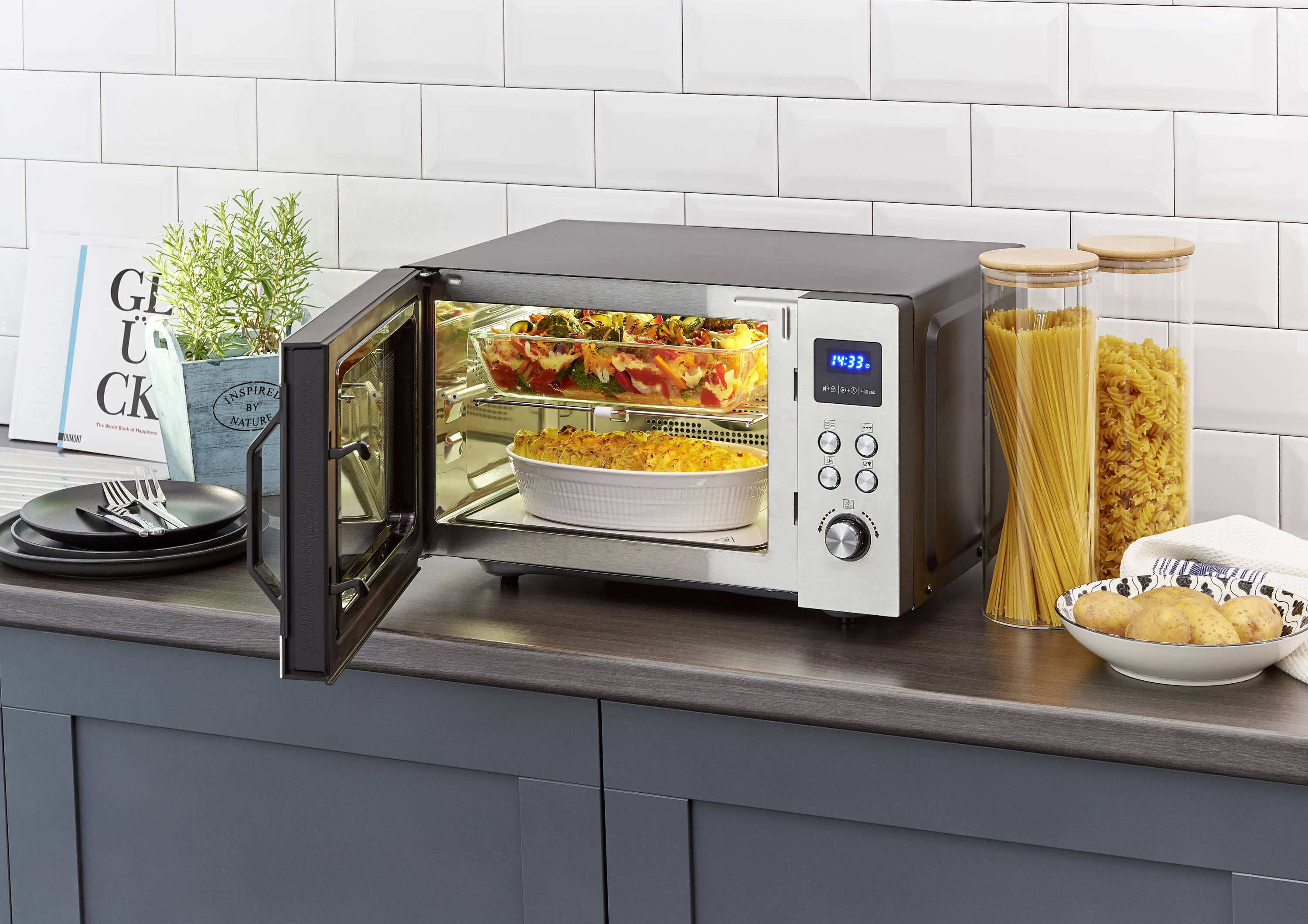 A table oven with a glass front shows two stacked baking dishes with baked, golden-brown bake inside.