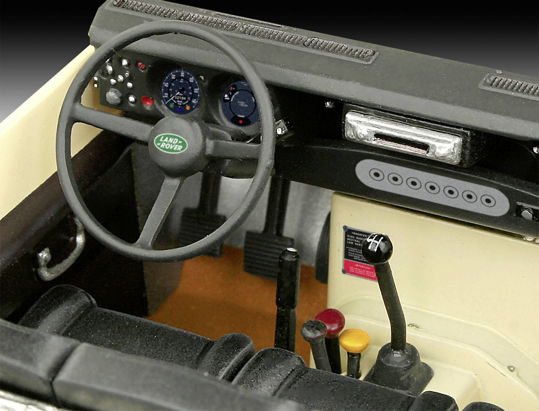 Interior of a car with steering wheel, dashboard and gear levers. A 'Land Rover' logo is visible on the steering wheel.