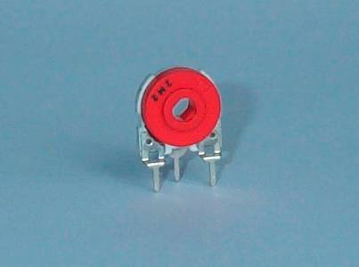 A red, round electronic component, possibly a trimmer or potentiometer, with two metal terminals.