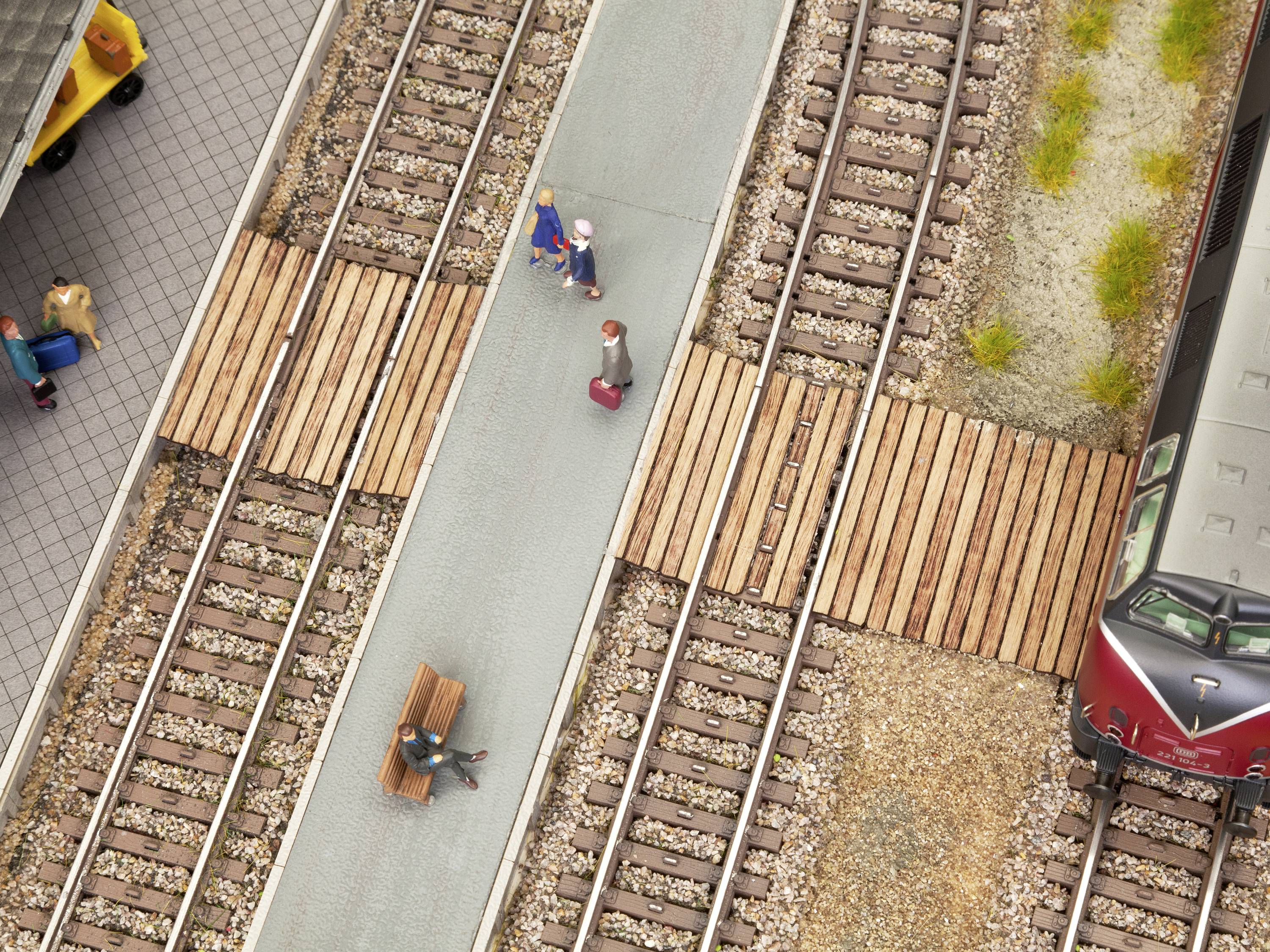 Aerial view of a railway station with multiple train tracks, a few people walking on the platform, and a stationary train.