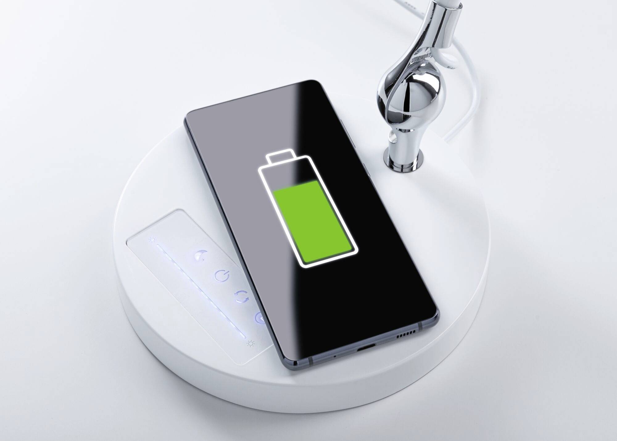 A smartphone is resting on a wireless charging pad. The screen displays a charging symbol with a green battery icon.