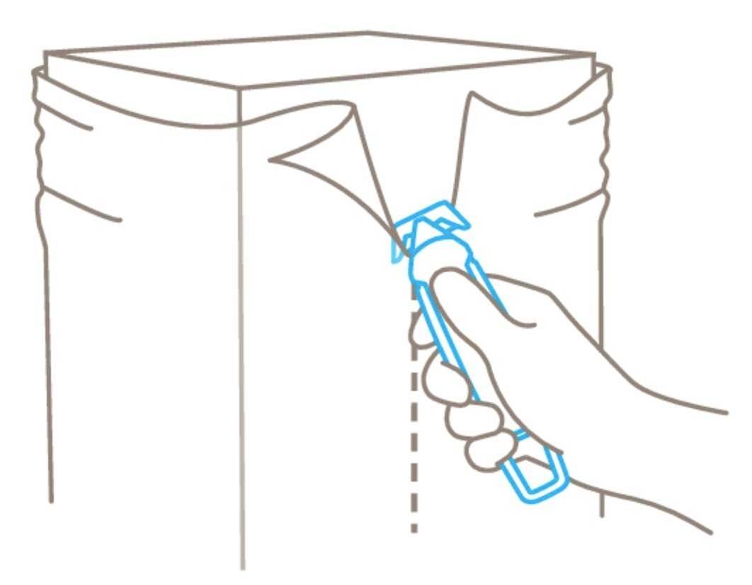 A hand uses an opener to break the sealed seams of a bag.