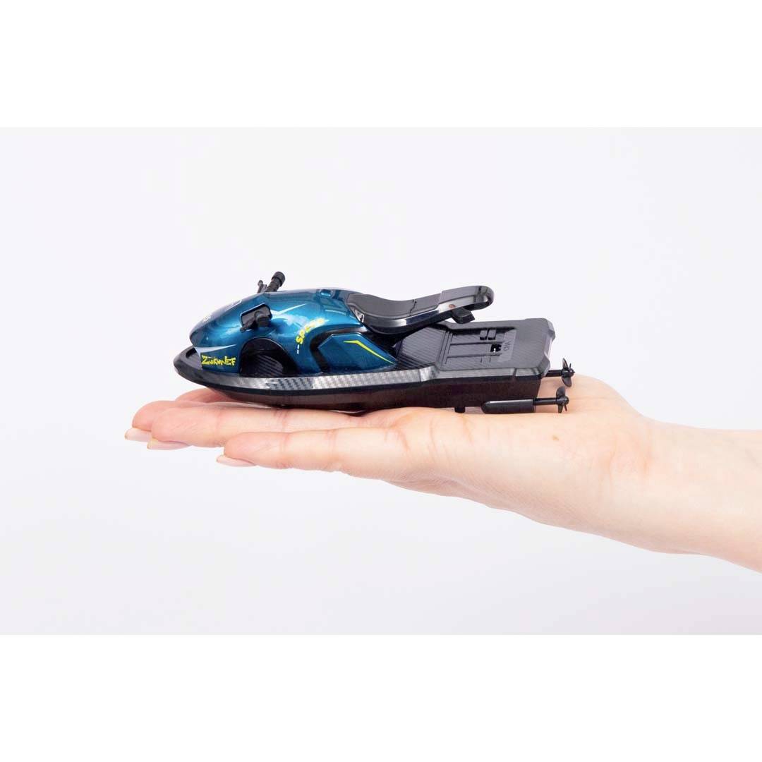 A hand is holding a small, blue-black model of a watercraft. The model is intricately designed and displays elegant lines.