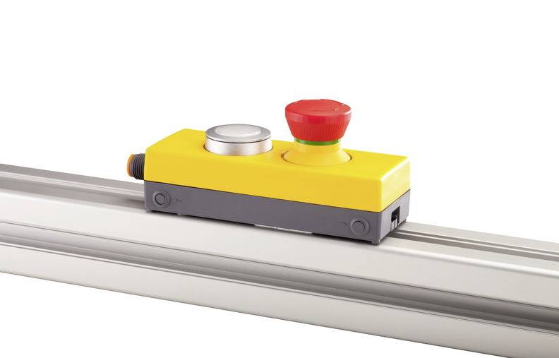 Yellow emergency stop module mounted on rail. Red push button for emergency shutdown, silver reset button beside it.