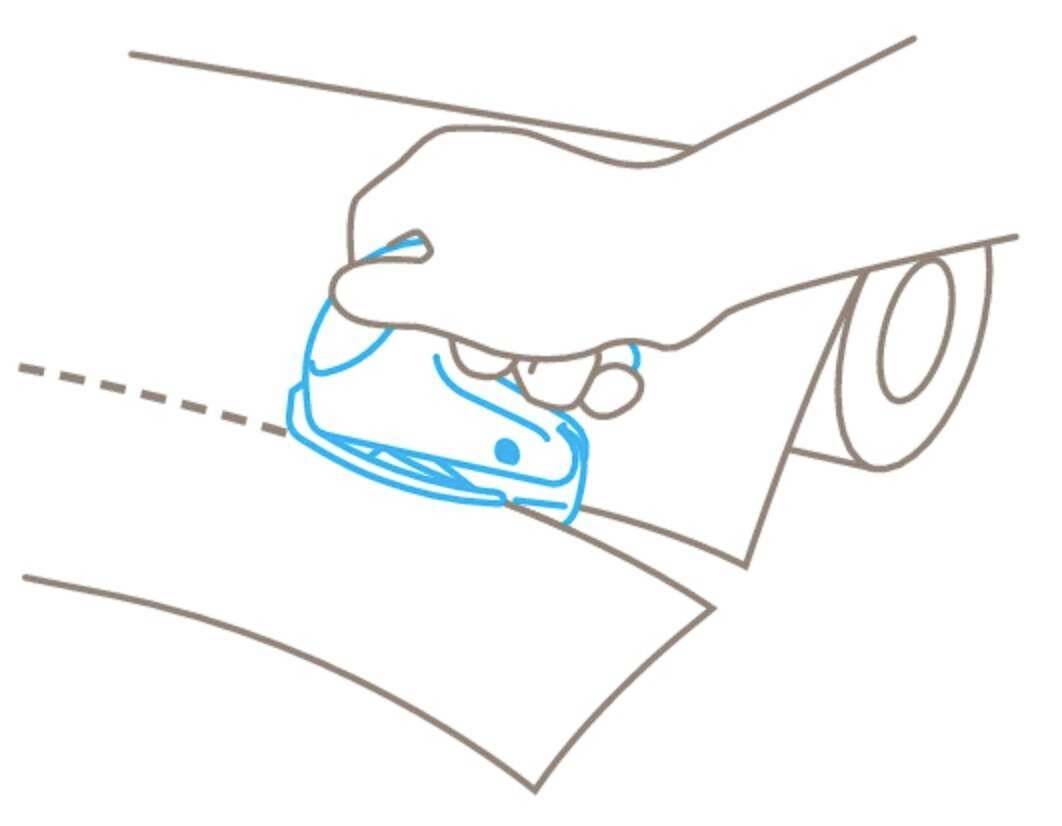 A hand is using a blue paper cutter to make a straight cut along a dotted line on paper.