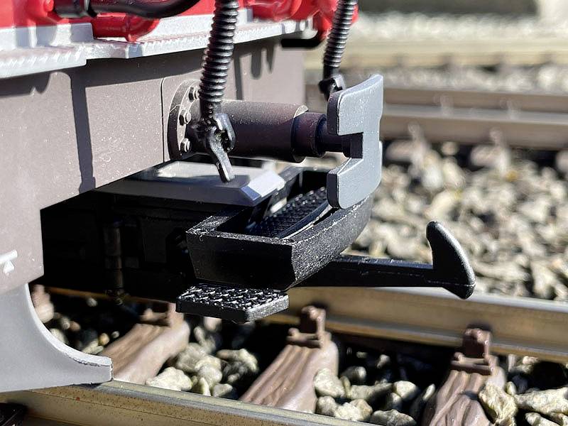 Close-up of a model railway coupling on tracks. Details of the coupling mechanism and ballast are visible in the background.