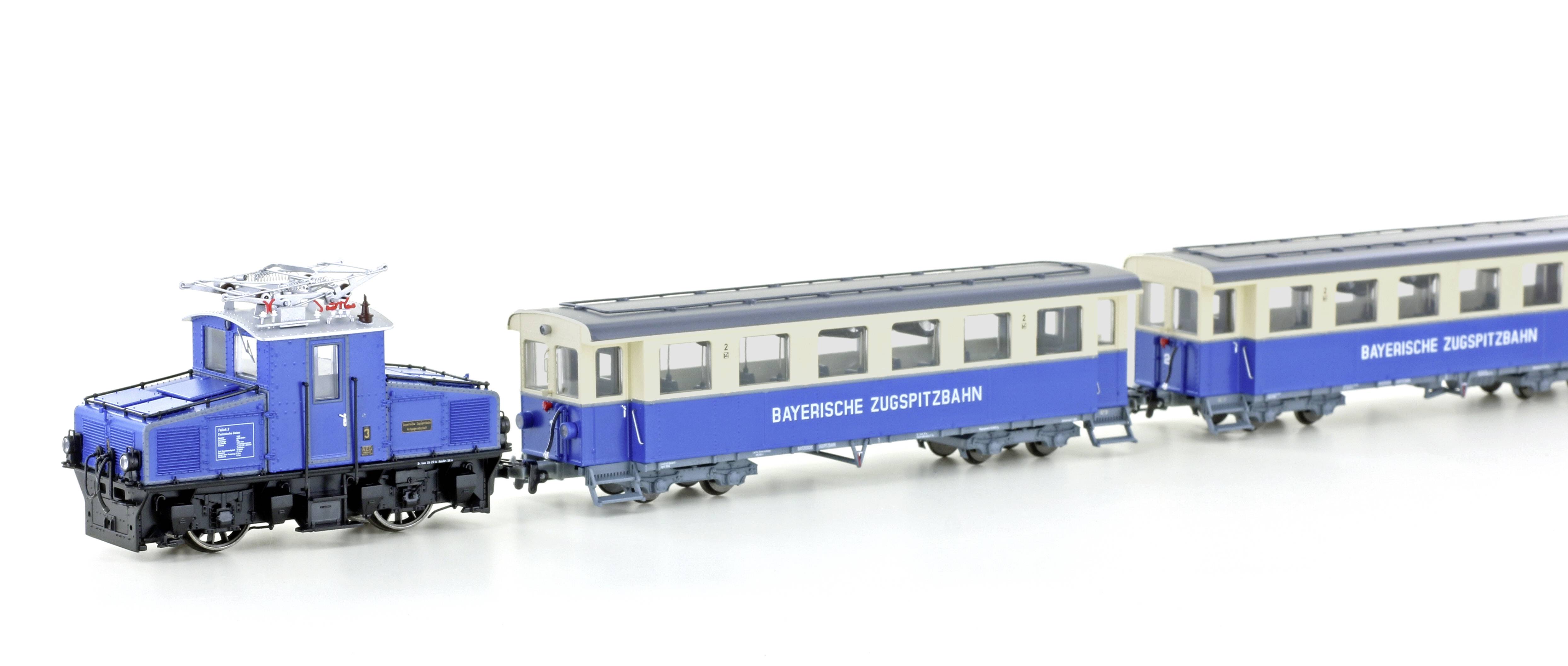 A blue and white miniature train with the inscription 'Bayerische Zugspitzbahn'. Locomotive and two carriages on a white background.