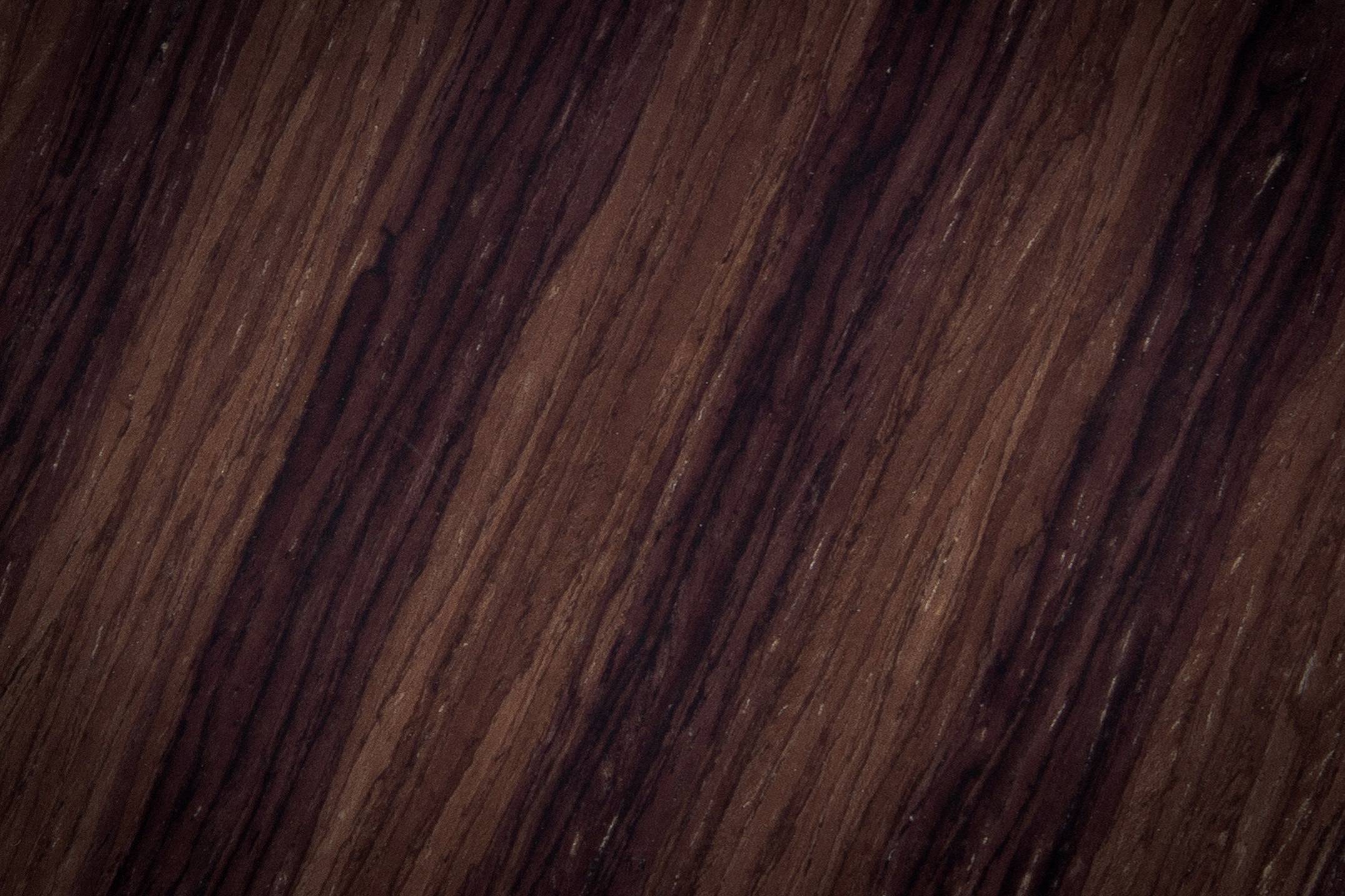 Wooden texture in dark brown colour with natural grain patterns and shading.