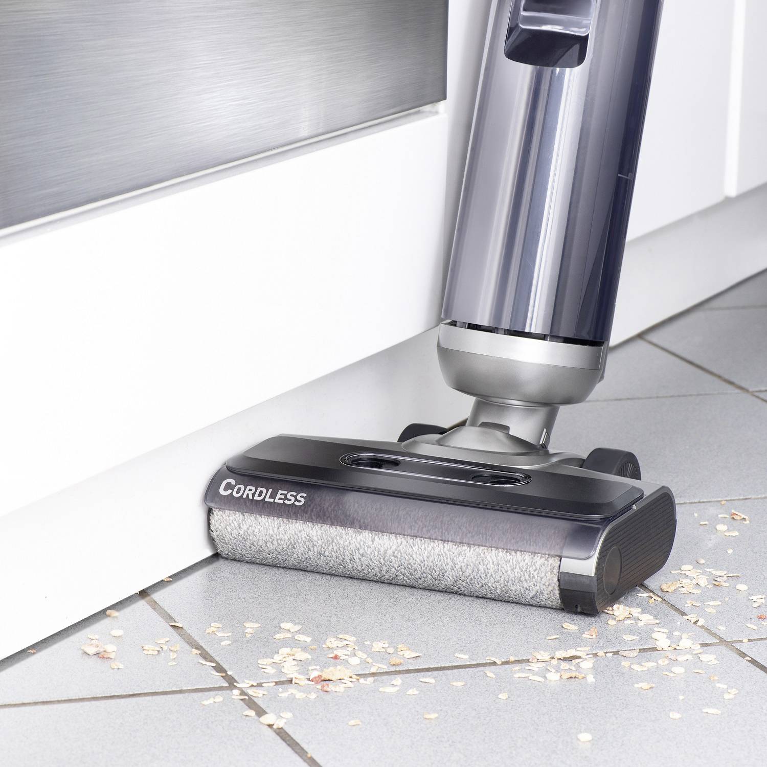 A cordless vacuum cleaner effectively cleans crumbs from the floor in a modern kitchen.