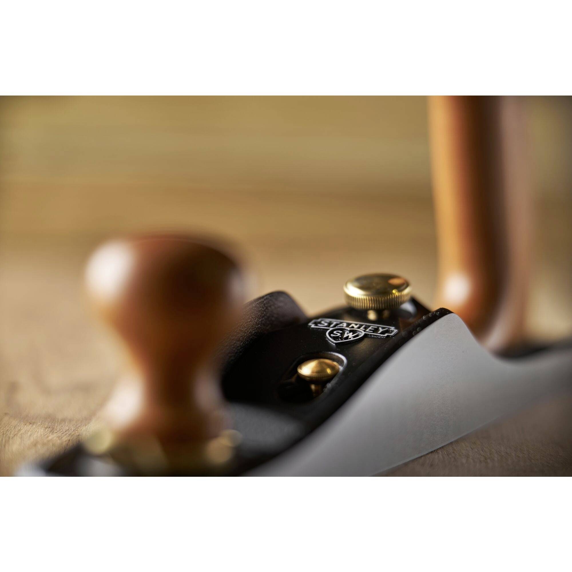 A blurry photograph of a plane on a wooden surface, focusing on the metal body with the 'Stanley' inscription.