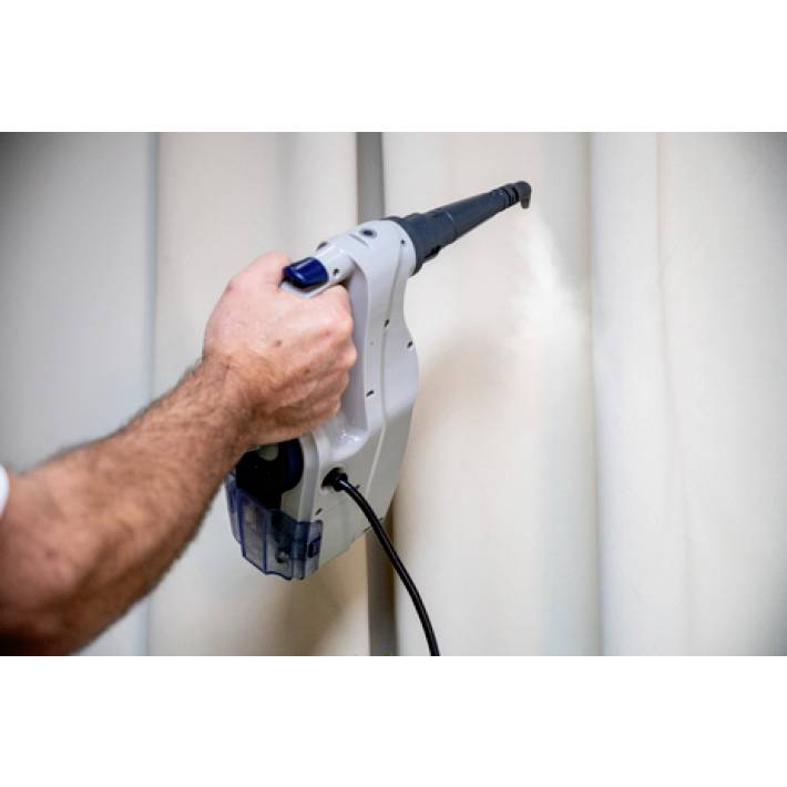 A person is cleaning a curtain with a steam cleaner. Their hand is holding the device, which is emitting steam onto the fabric.