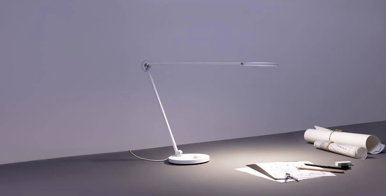 A slender desk lamp illuminates a workspace with architectural plans, a ruler, and a pen, all ready for work.