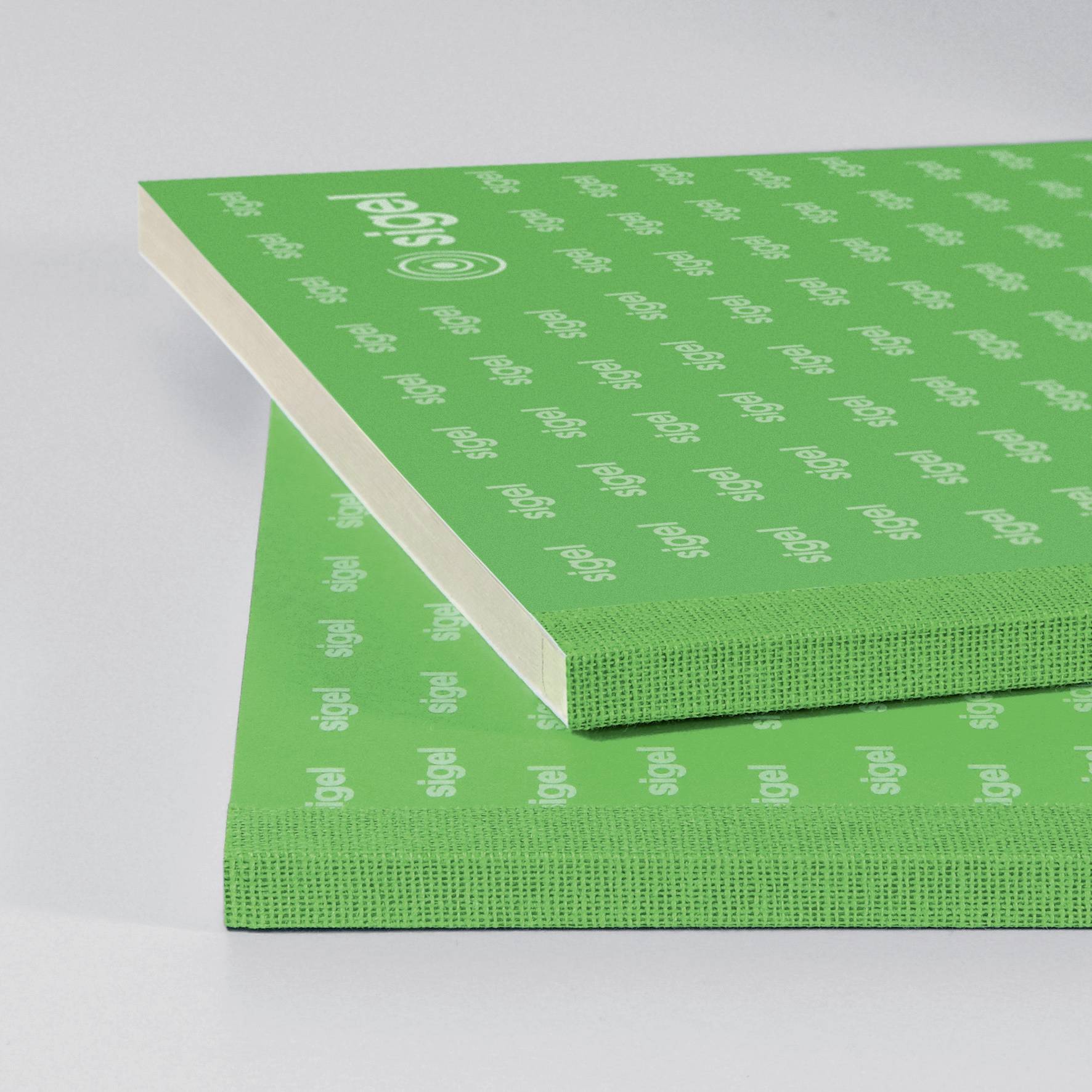 A stack of green notepads lies on a table, printed with the 'sigel' logo.