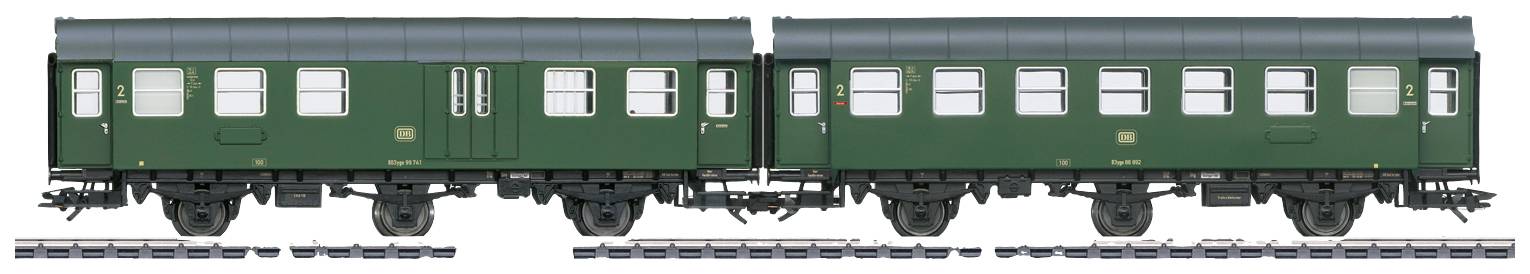 Two green railway carriages without a locomotive on tracks, symmetrically arranged, with multiple windows and a double door.
