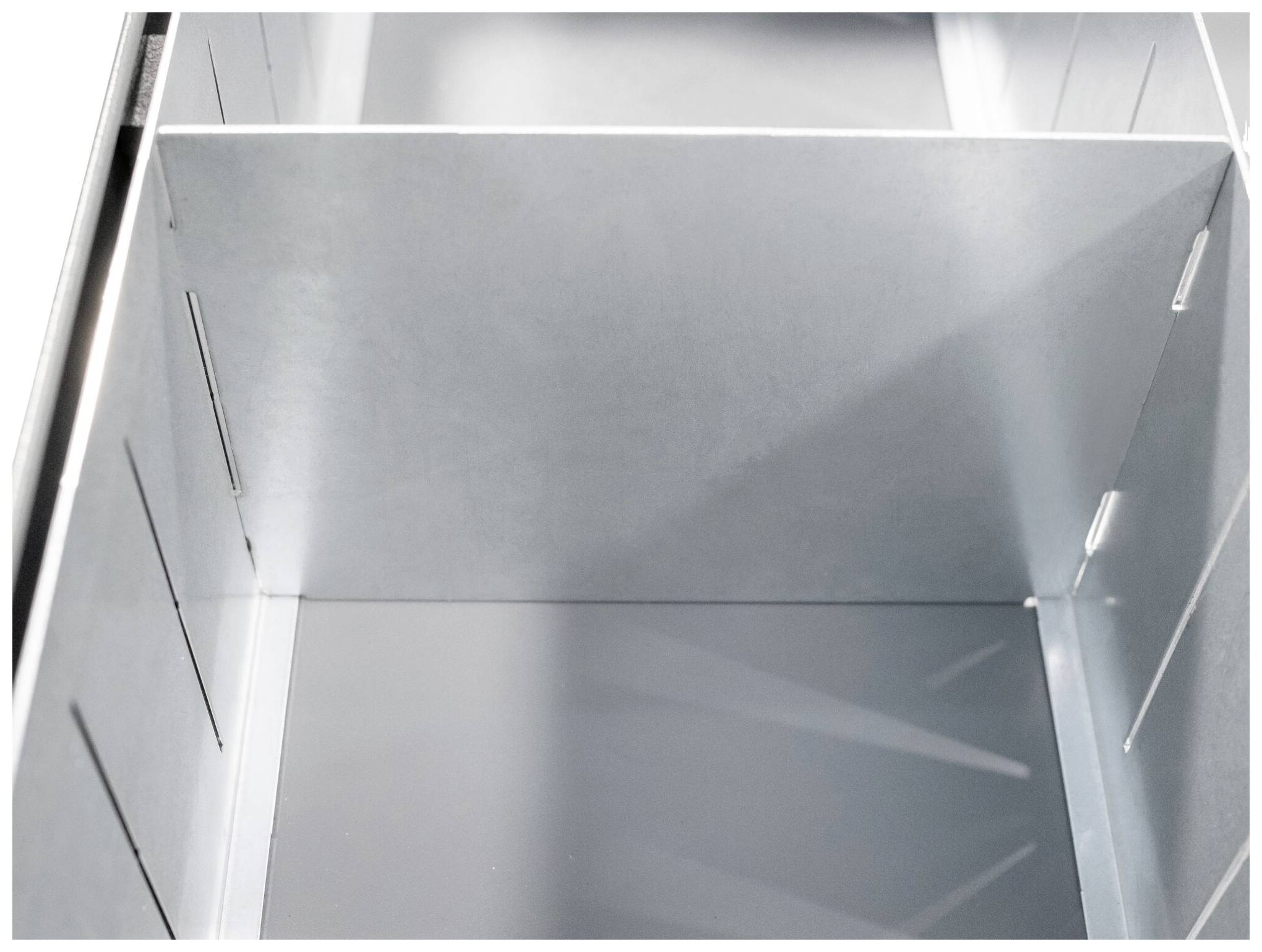 Interior of a metallic enclosure with multiple compartments and slots, suitable for organising technical components.(Note: This translation uses British English spelling, such as 