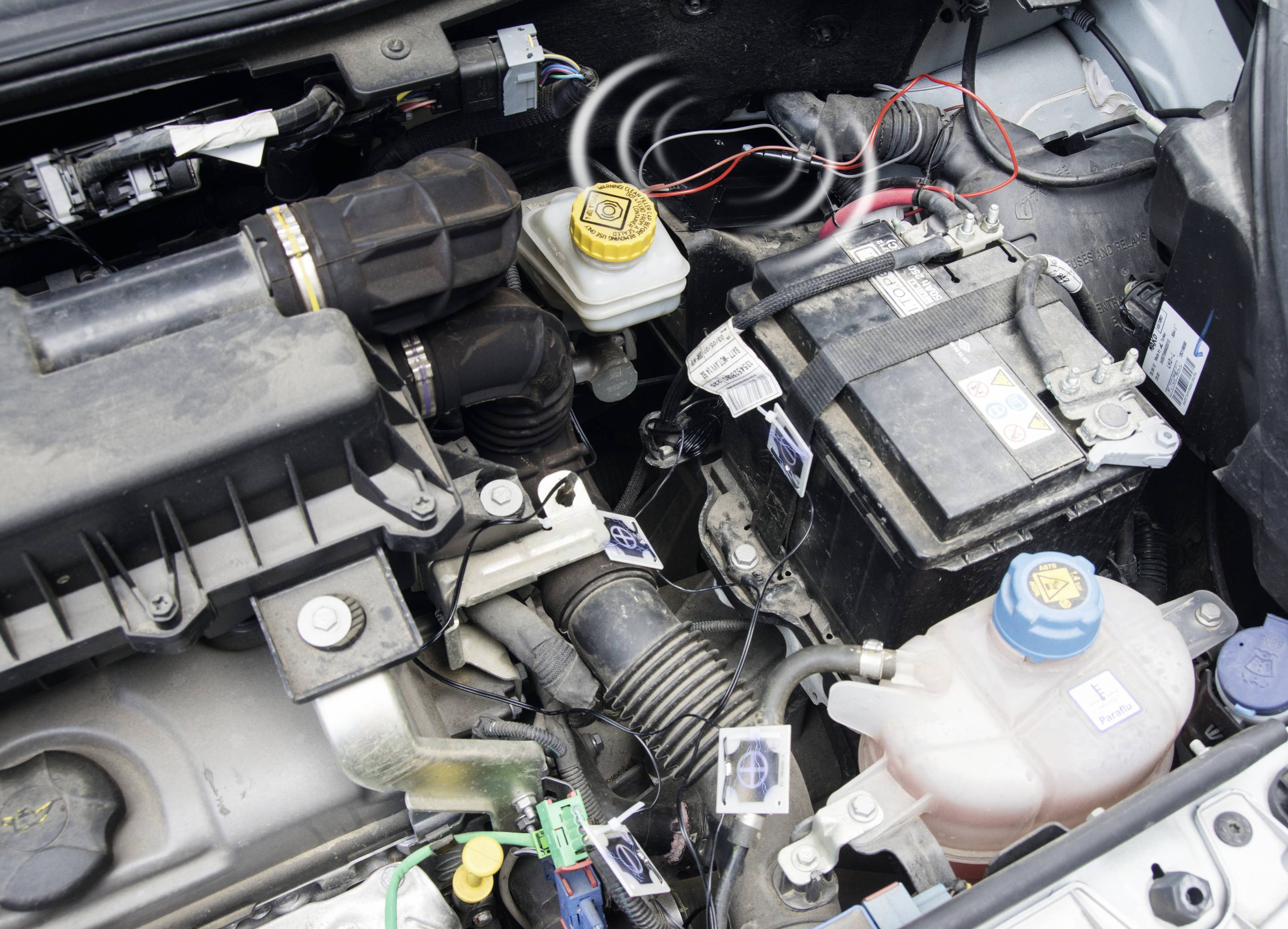 Engine compartment with battery, coolant reservoir, air filter housing and brake fluid reservoir. Cable connections visible.