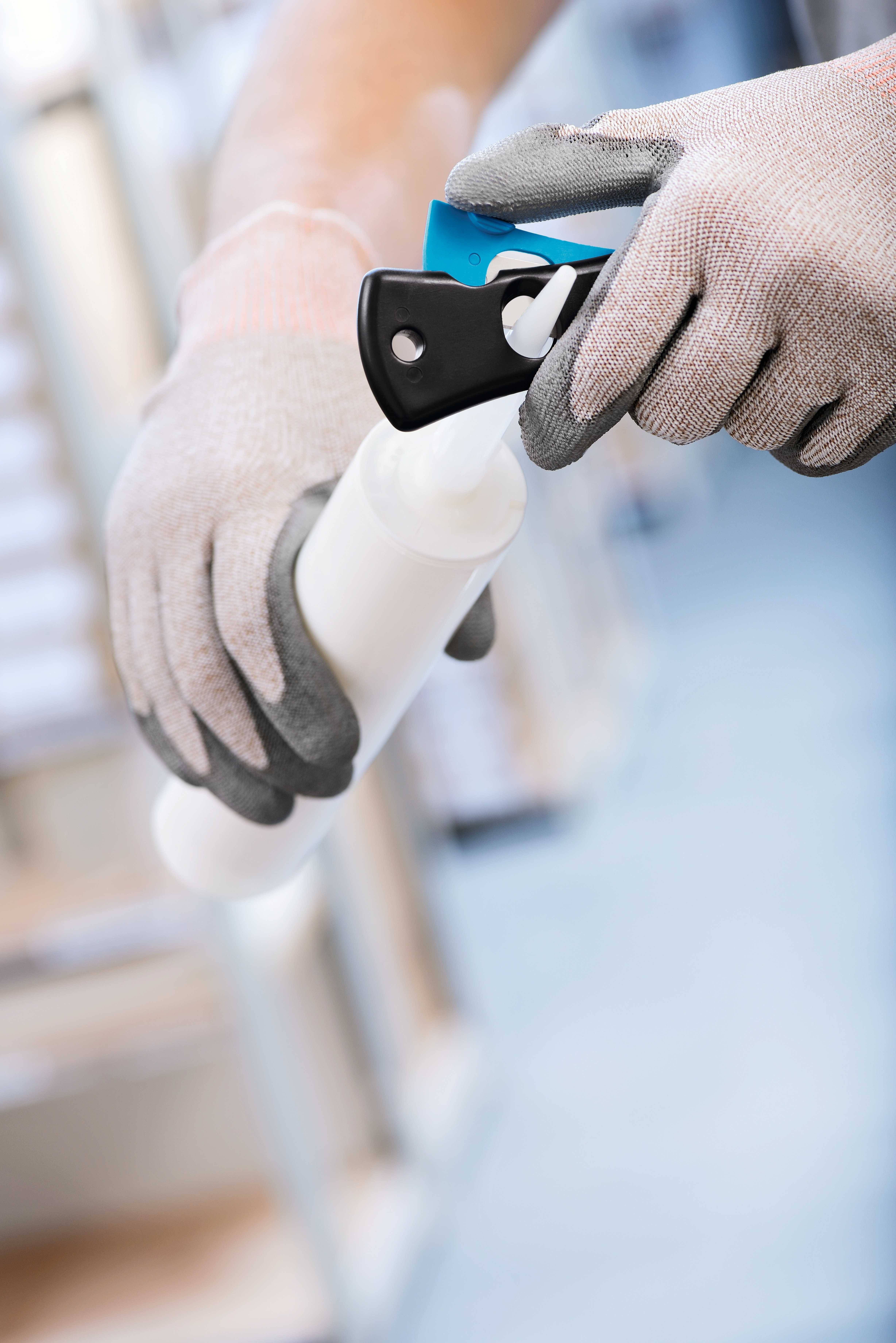 A person wearing gloves is holding a spray bottle and removing the protective cap, possibly in preparation for cleaning or disinfecting.