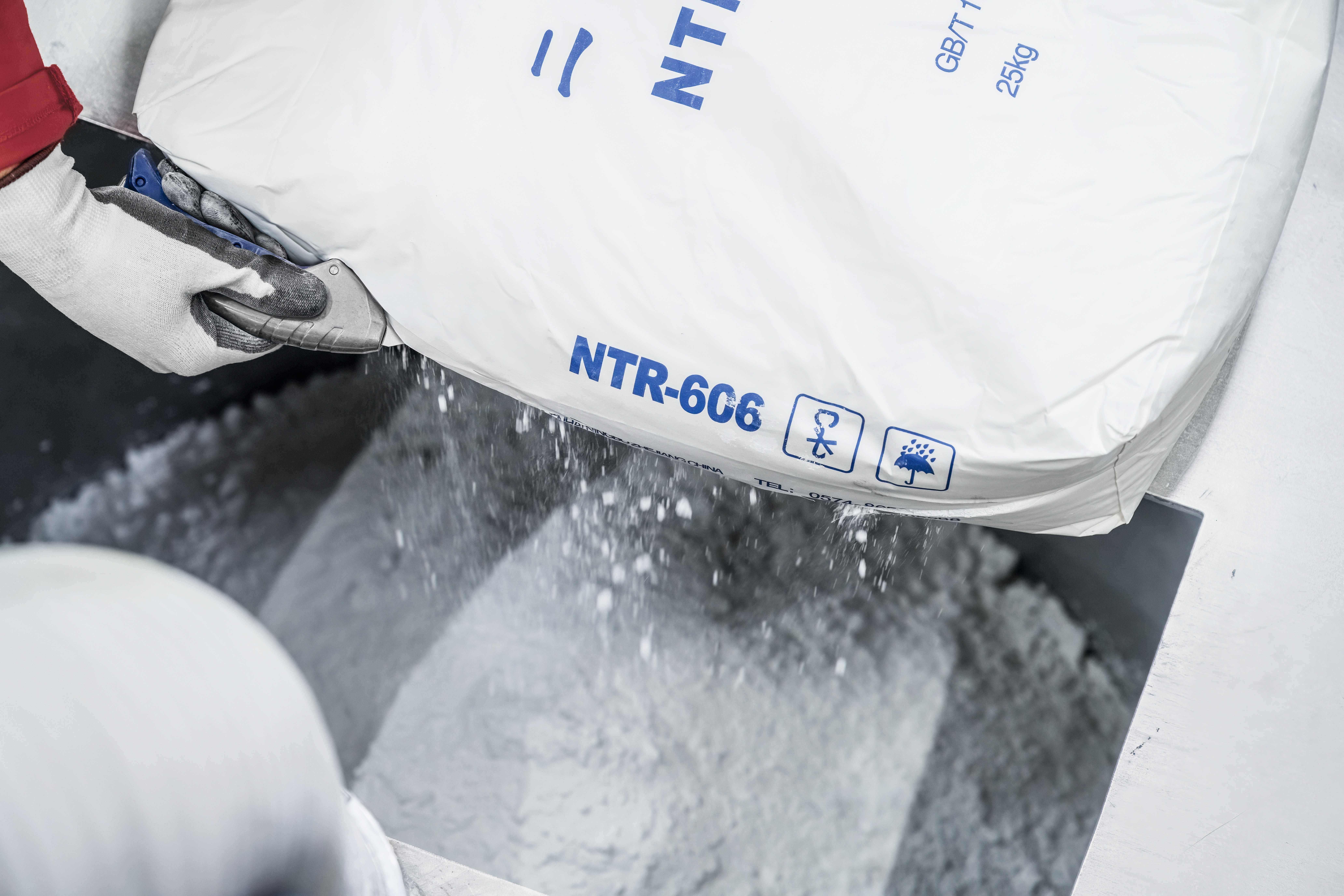 'A person is pouring white powder contents from a sack labelled 