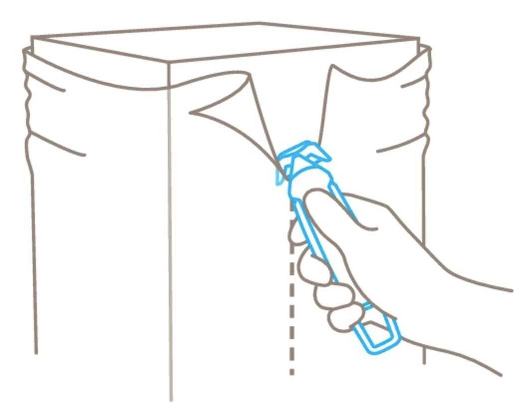 A hand cuts along a dotted line on packaging with a knife.