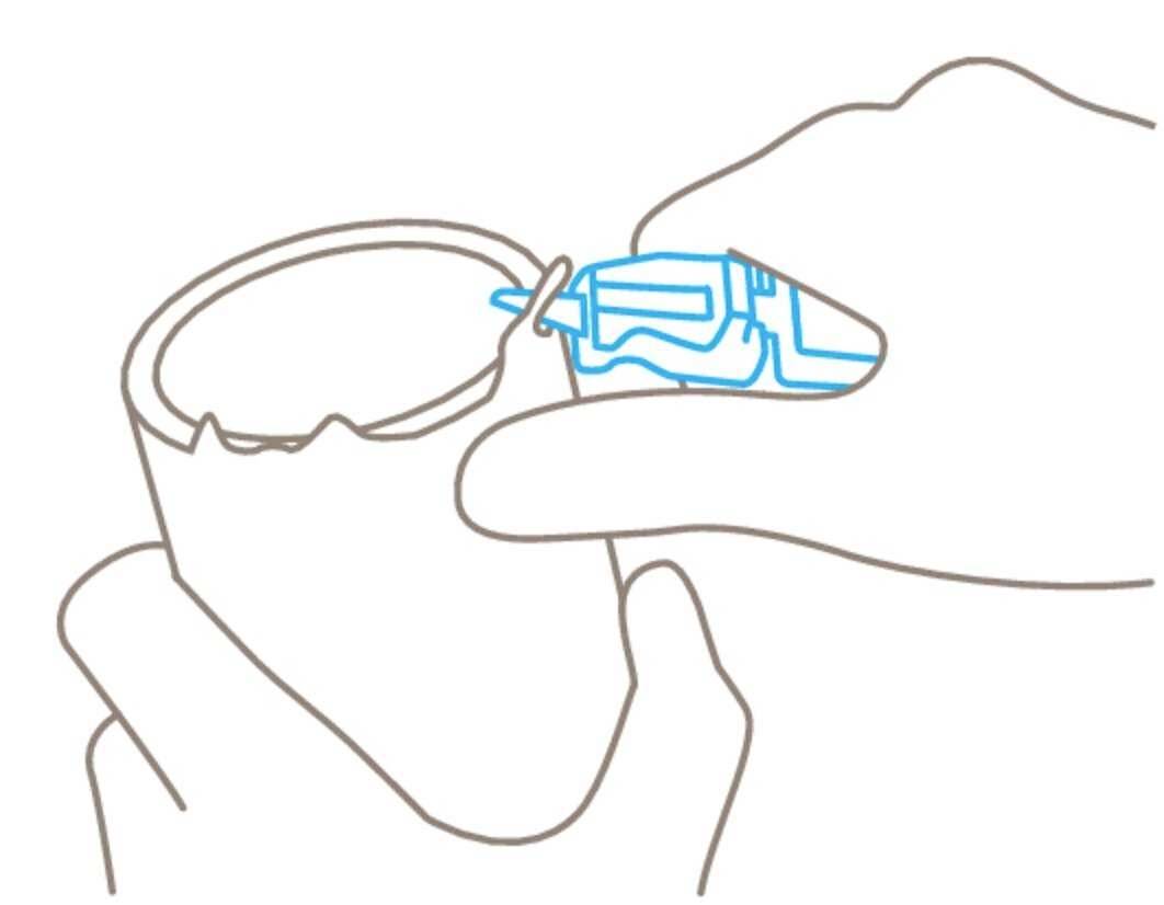 A hand holds a mug, while the other hand applies adhesive to the rim of the mug.