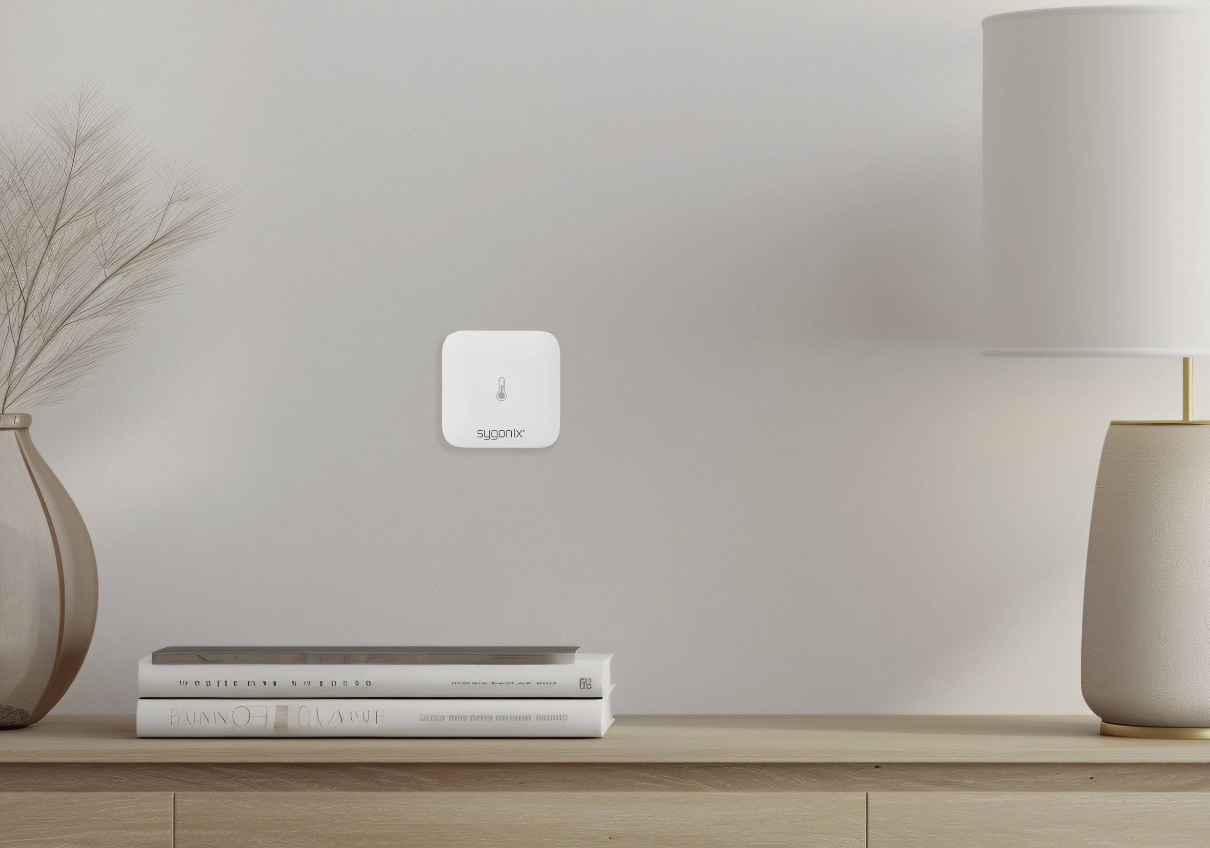 A minimalist desk with a vase, books and lamp. A small white sensor on the wall displays 'supreme'.