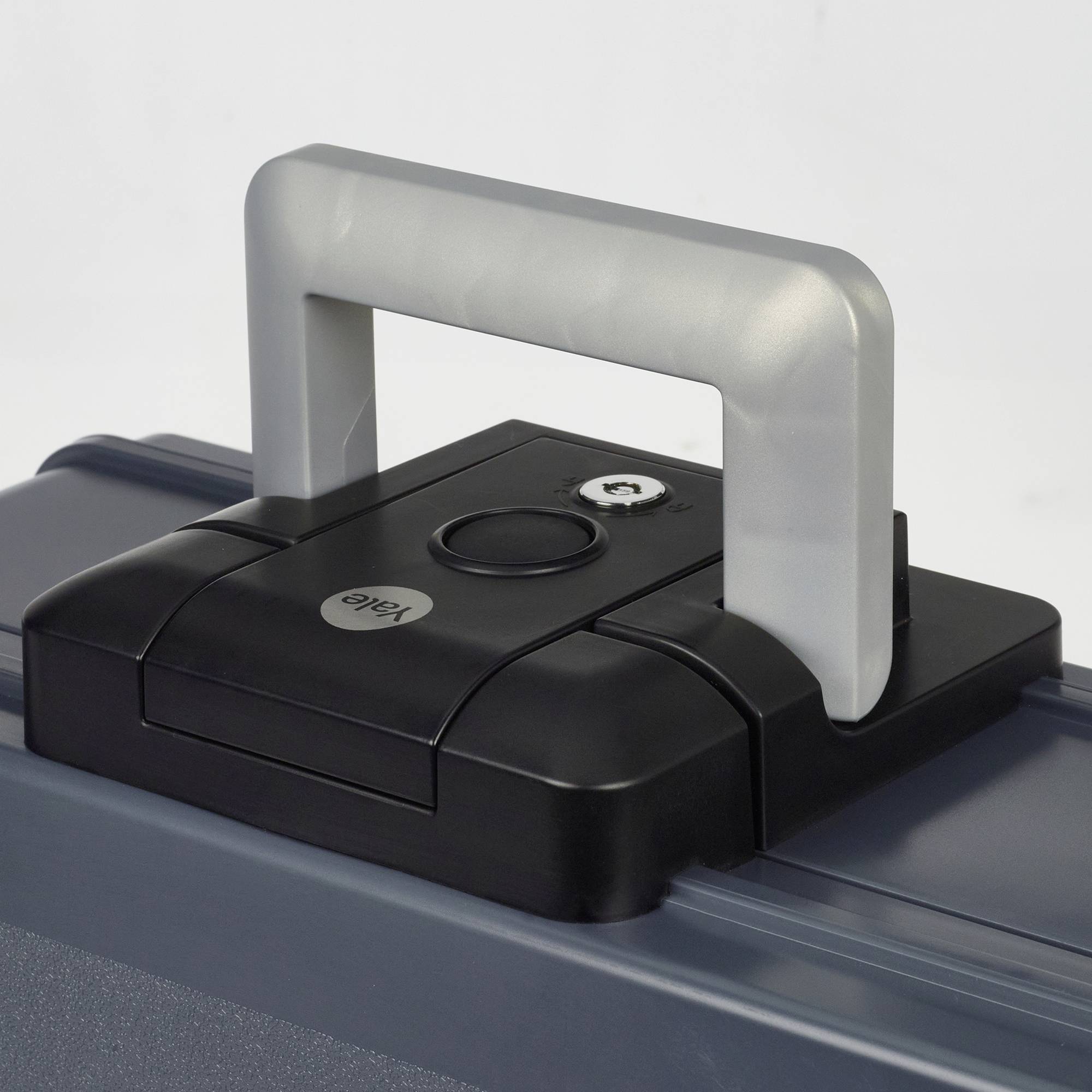 A grey suitcase with a silver handle. On the top surface, there is a small latch with a round key mechanism.