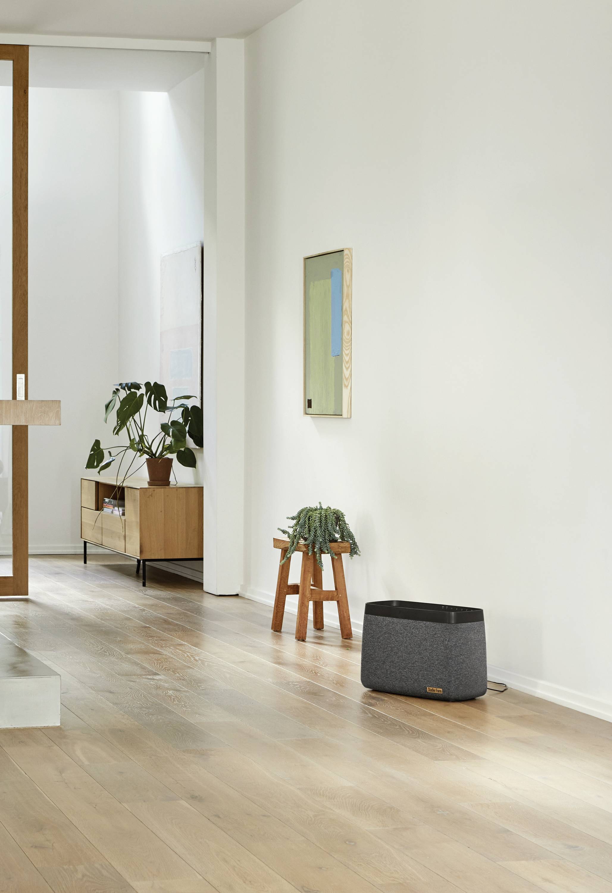 Elegant, modern living room with wooden flooring, minimalist furniture, plants and plenty of natural light.