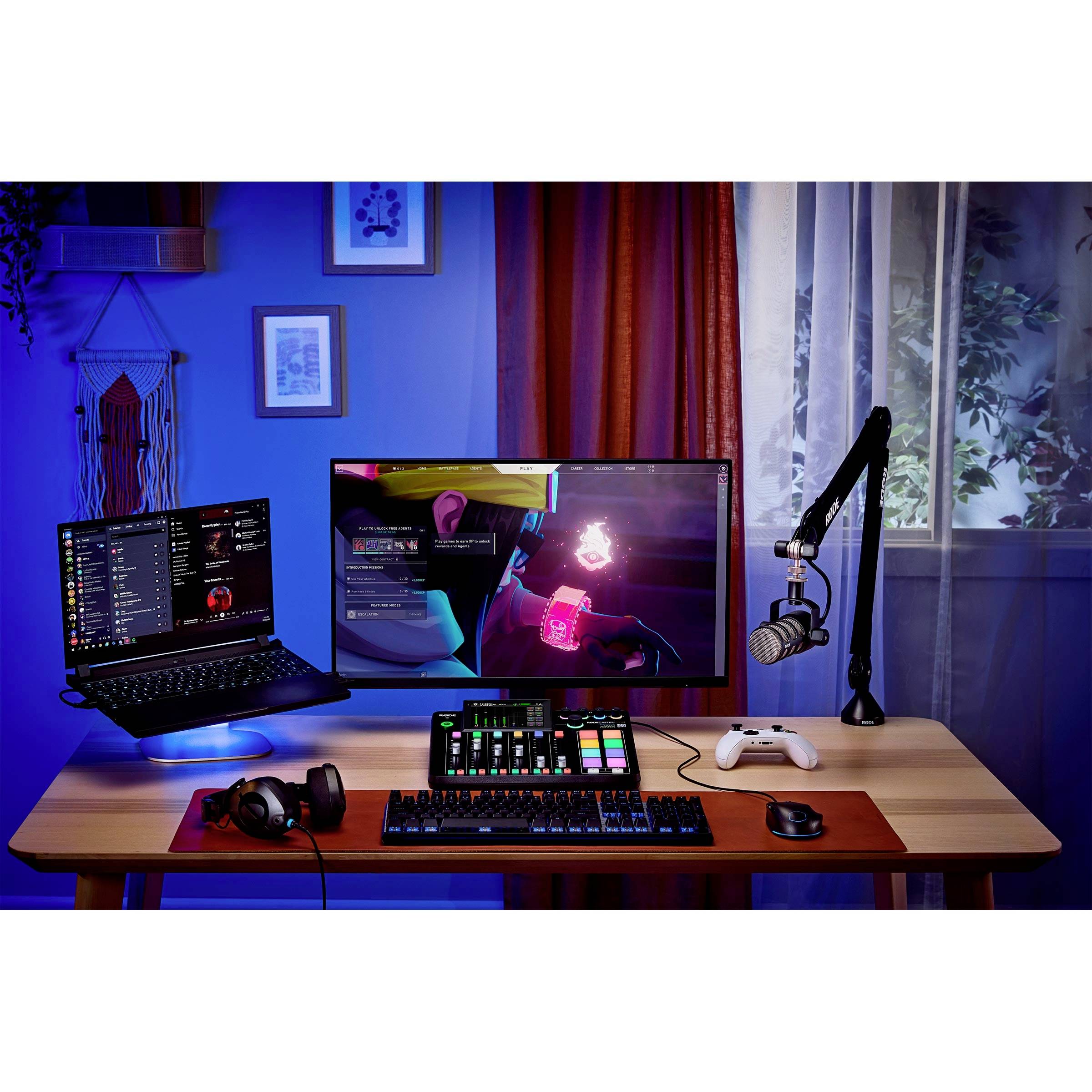 A desk with a laptop, monitor, streaming microphone, headphones and controller. Suitable for gaming or creative work.
