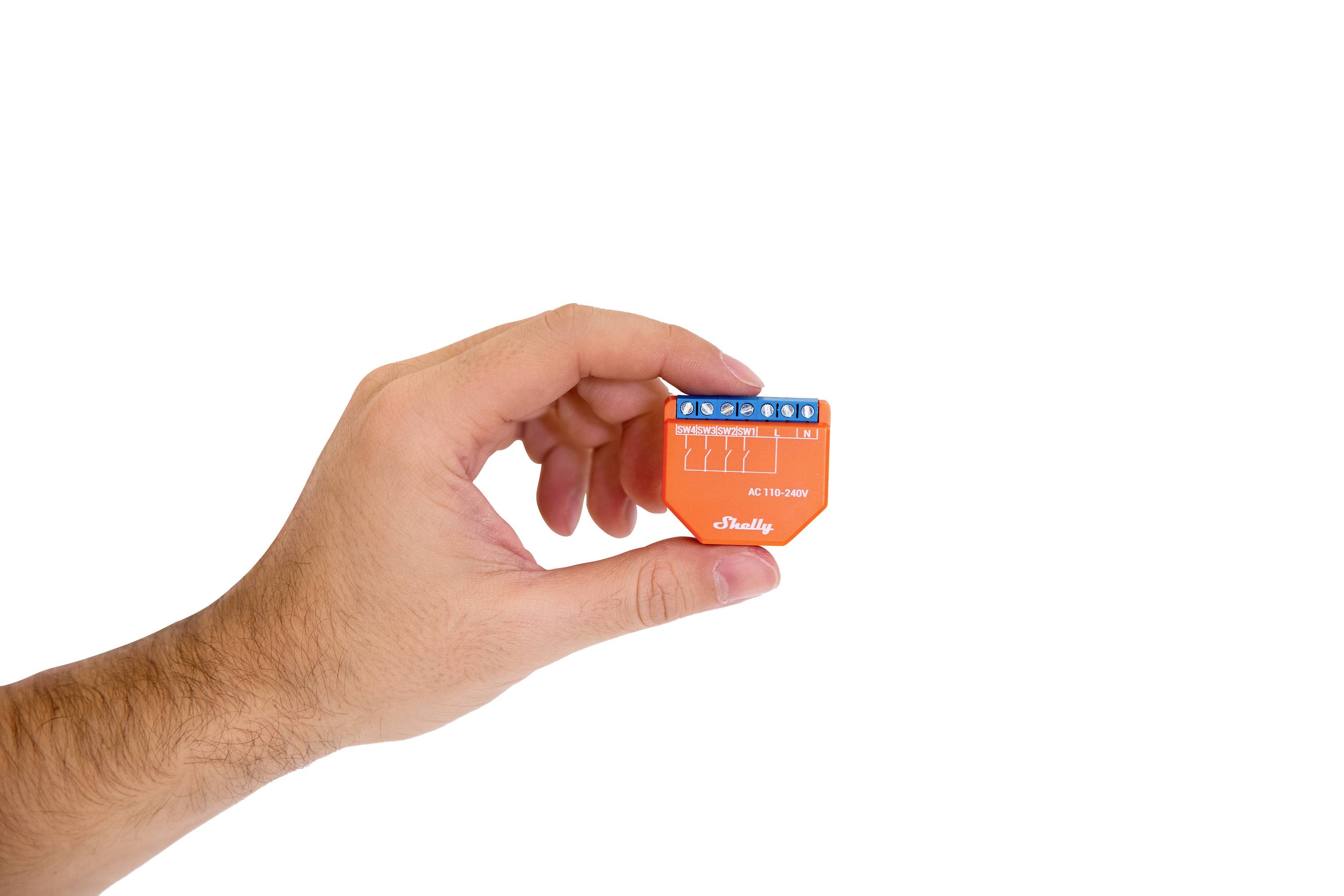 A hand is holding a small orange device with a blue top surface and labelling.