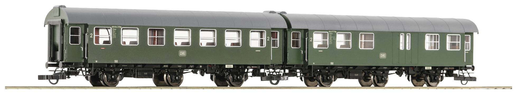 A green railway carriage with multiple windows on a track, side view.