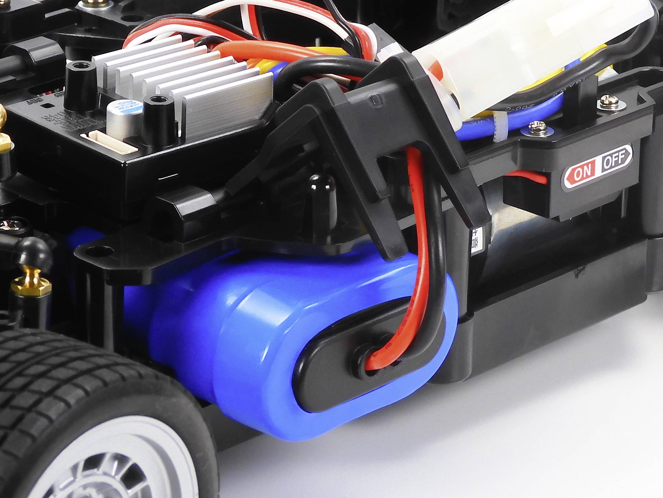 Close-up of a remote-controlled car chassis with visible wiring and an on/off switch.