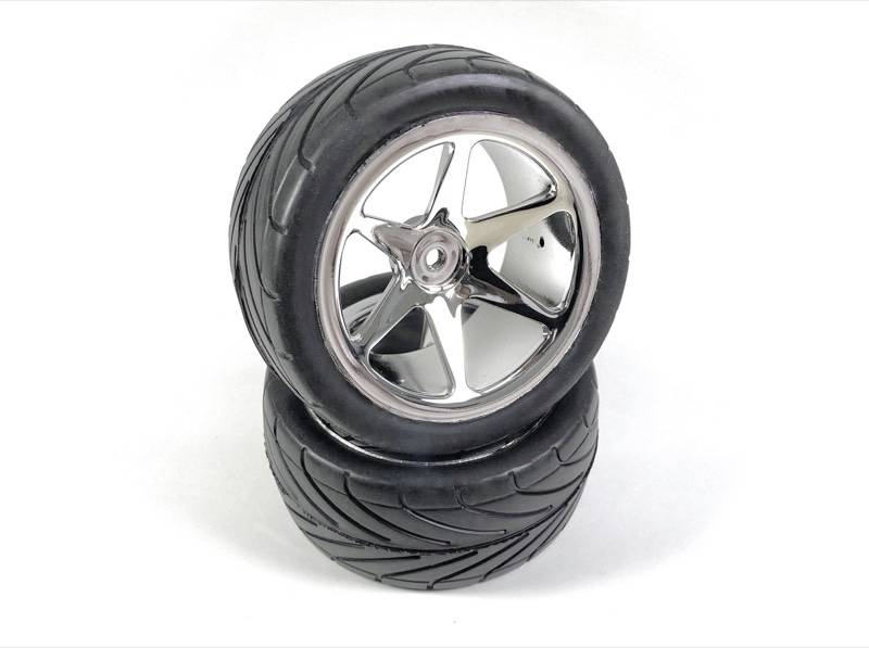 Two black car tyres with gleaming rims are stacked. The tyres have a deep tread pattern.