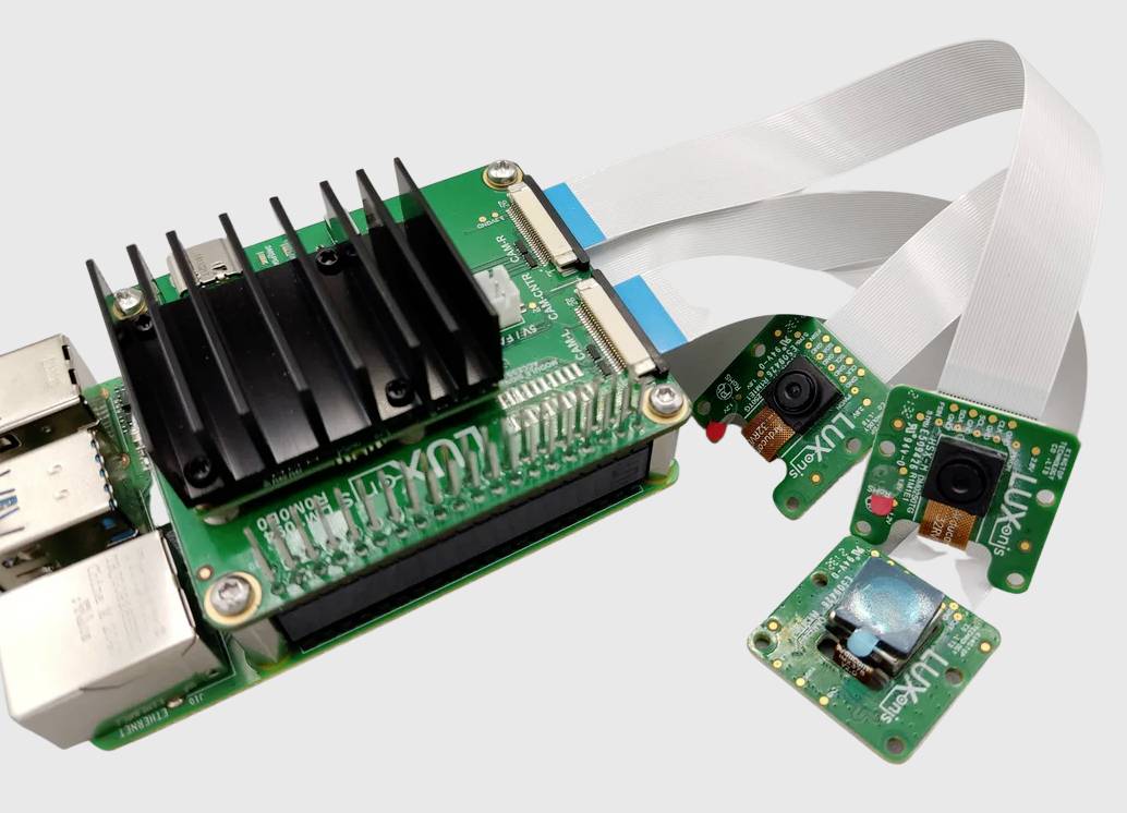 A green developer board with a heatsink is connected to three small camera modules. Developers use it for image capture or computer vision projects.