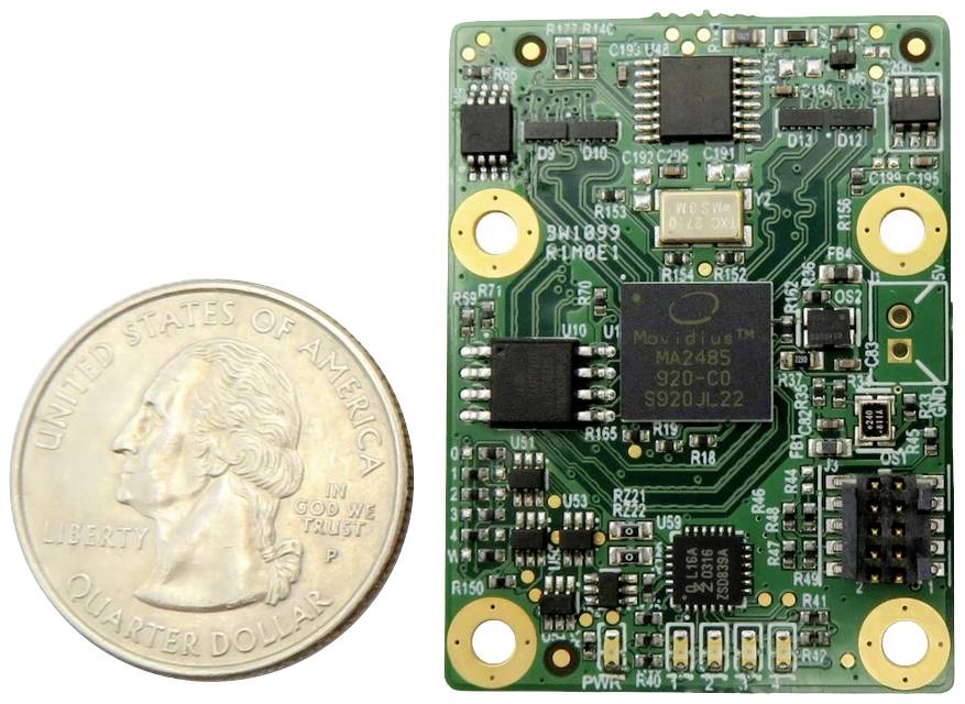 A green printed circuit board with electronic components next to a US quarter-dollar coin for size comparison.
