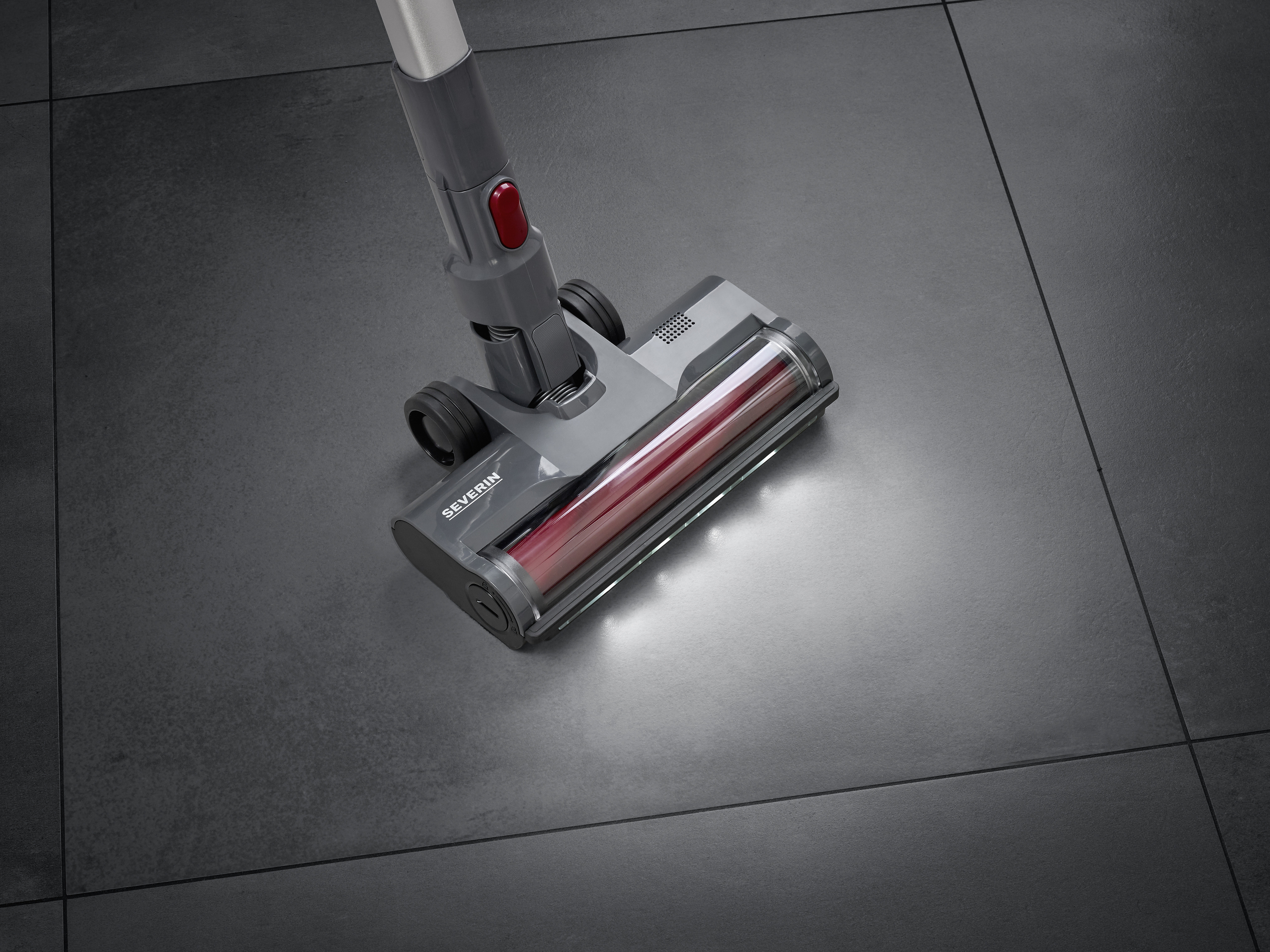 A vacuum cleaner with LED lights cleans dark tiles, with the floor showing a gleaming, clean area.