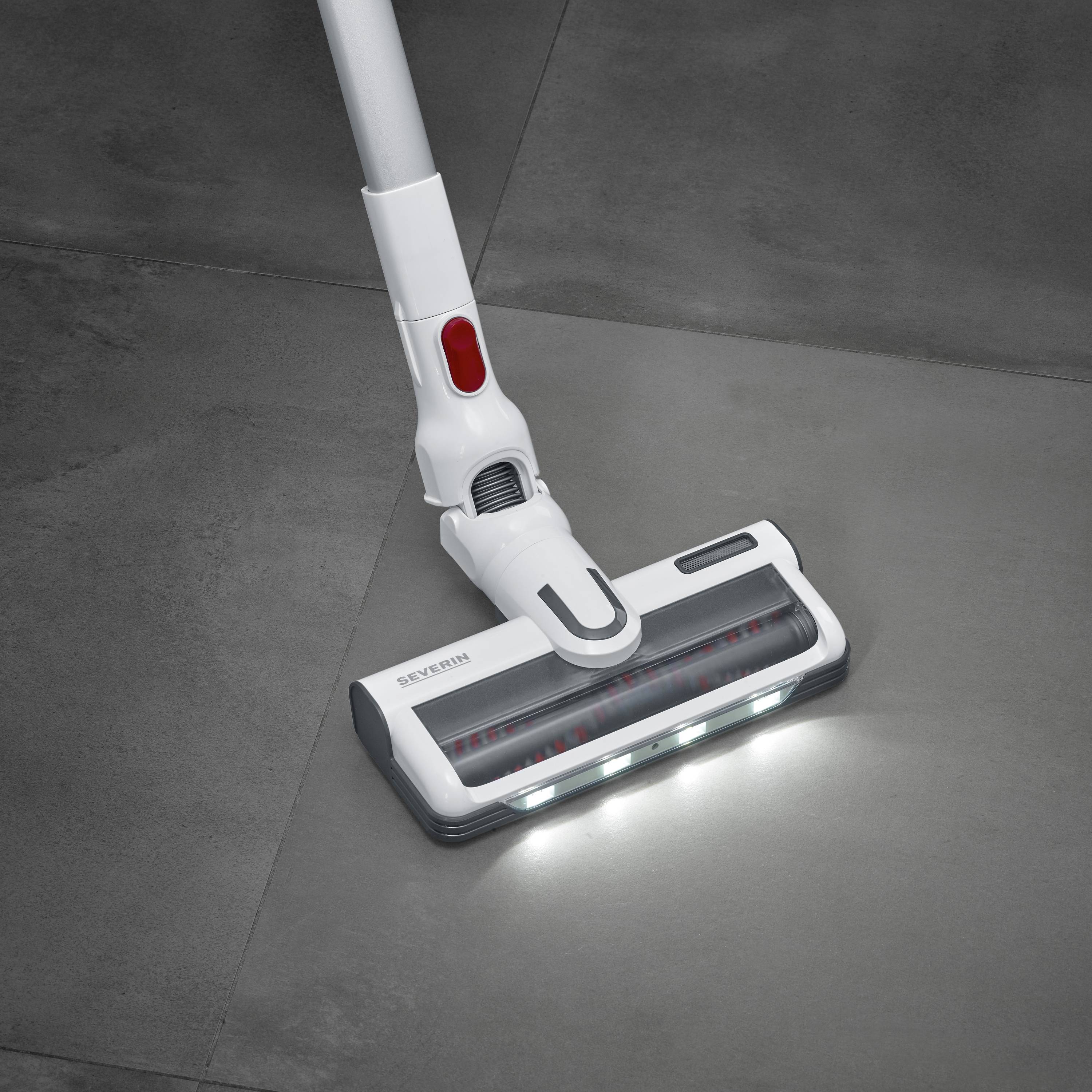 A white vacuum head with LED lights gliding across a dark tiled floor.