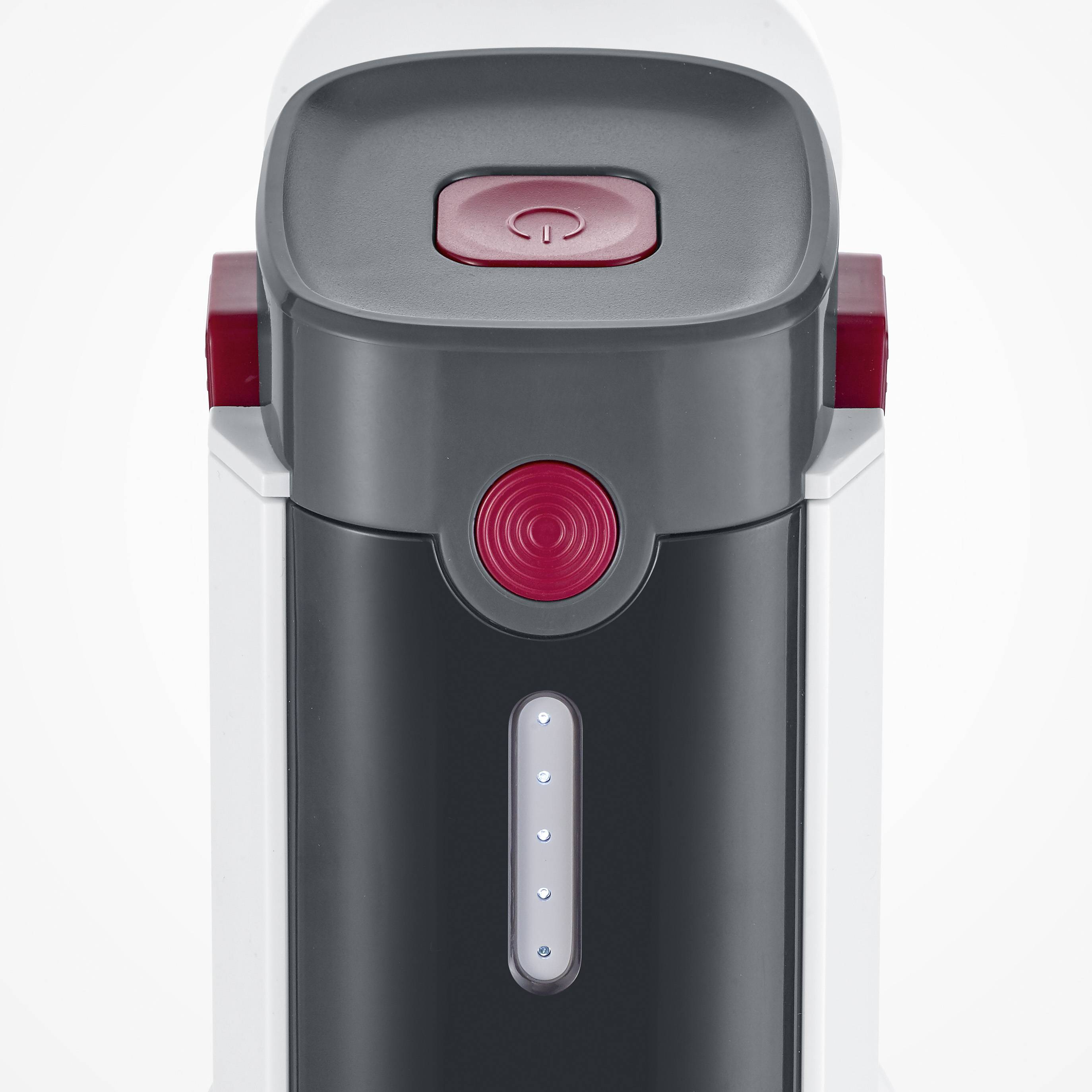 Coffee machine viewed from above with a red control button and indicator lights on the front panel.