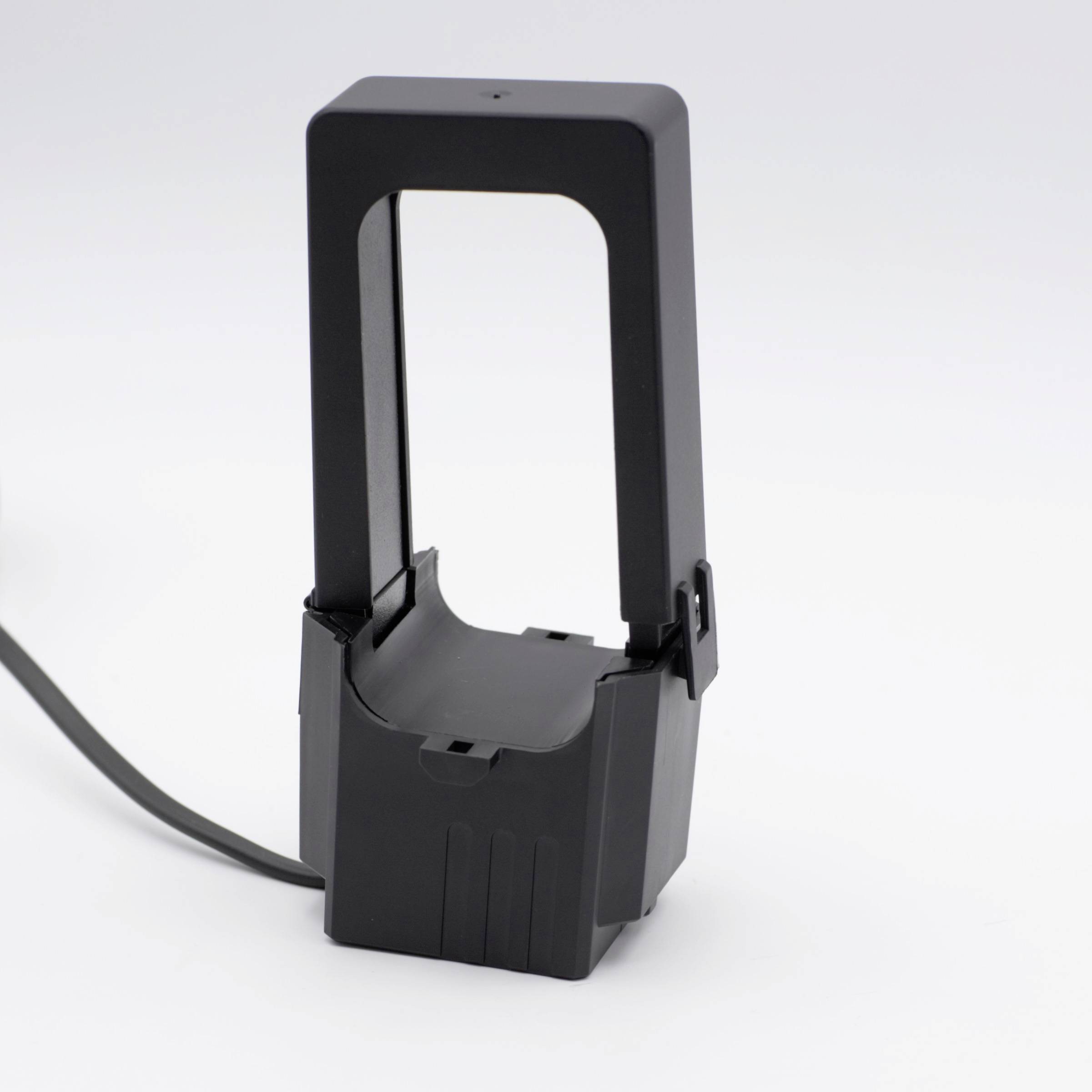 A black, rectangular plastic device with an open frame and cables. Possibly an electronic charger or a mount.