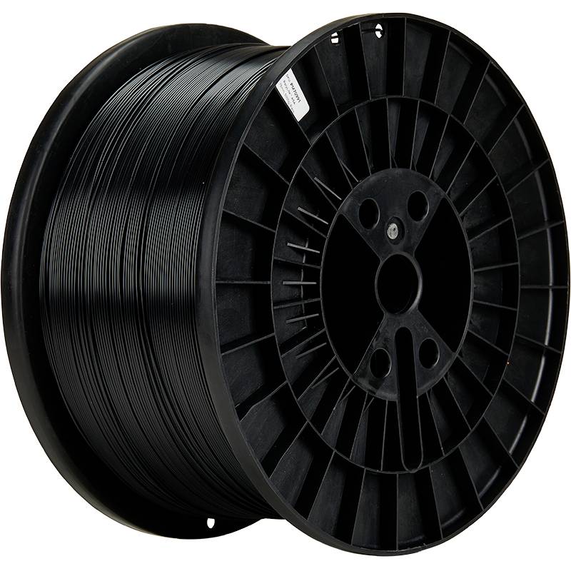 A large, black spool with plastic filament, likely for a 3D printer, stands upright; the spool is almost full.