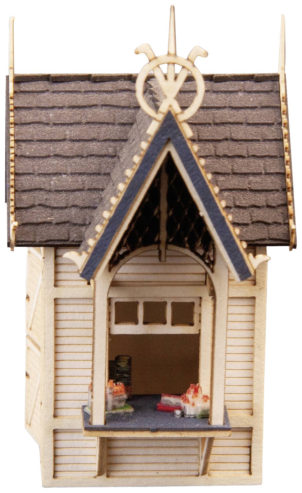 Small wooden model of a house with a steep roof and open windows. Intricately decorated and left in its natural colouring.