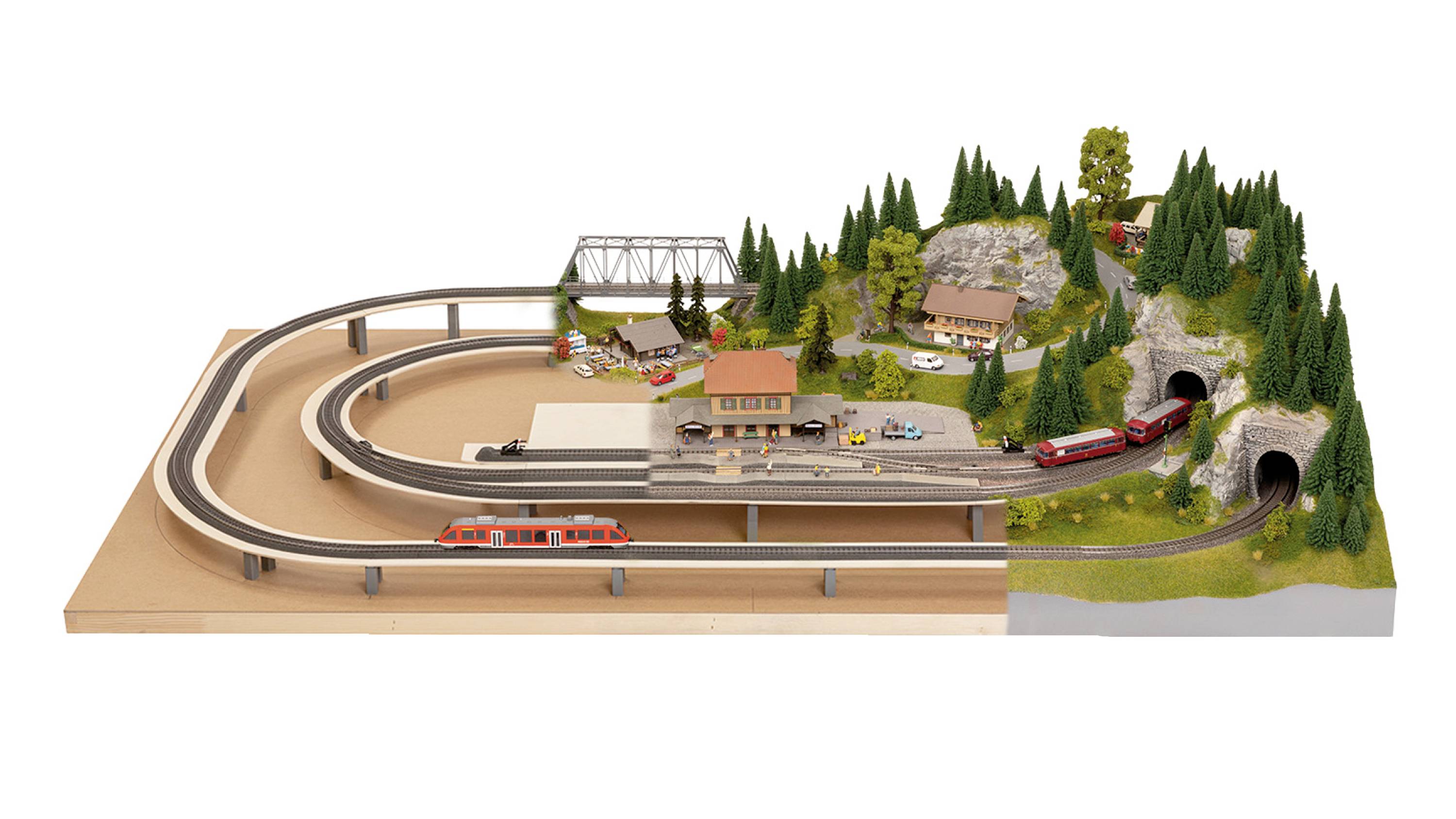 Miniature model of a landscape with railway track and trains, bridge and station building, surrounded by trees and small buildings.