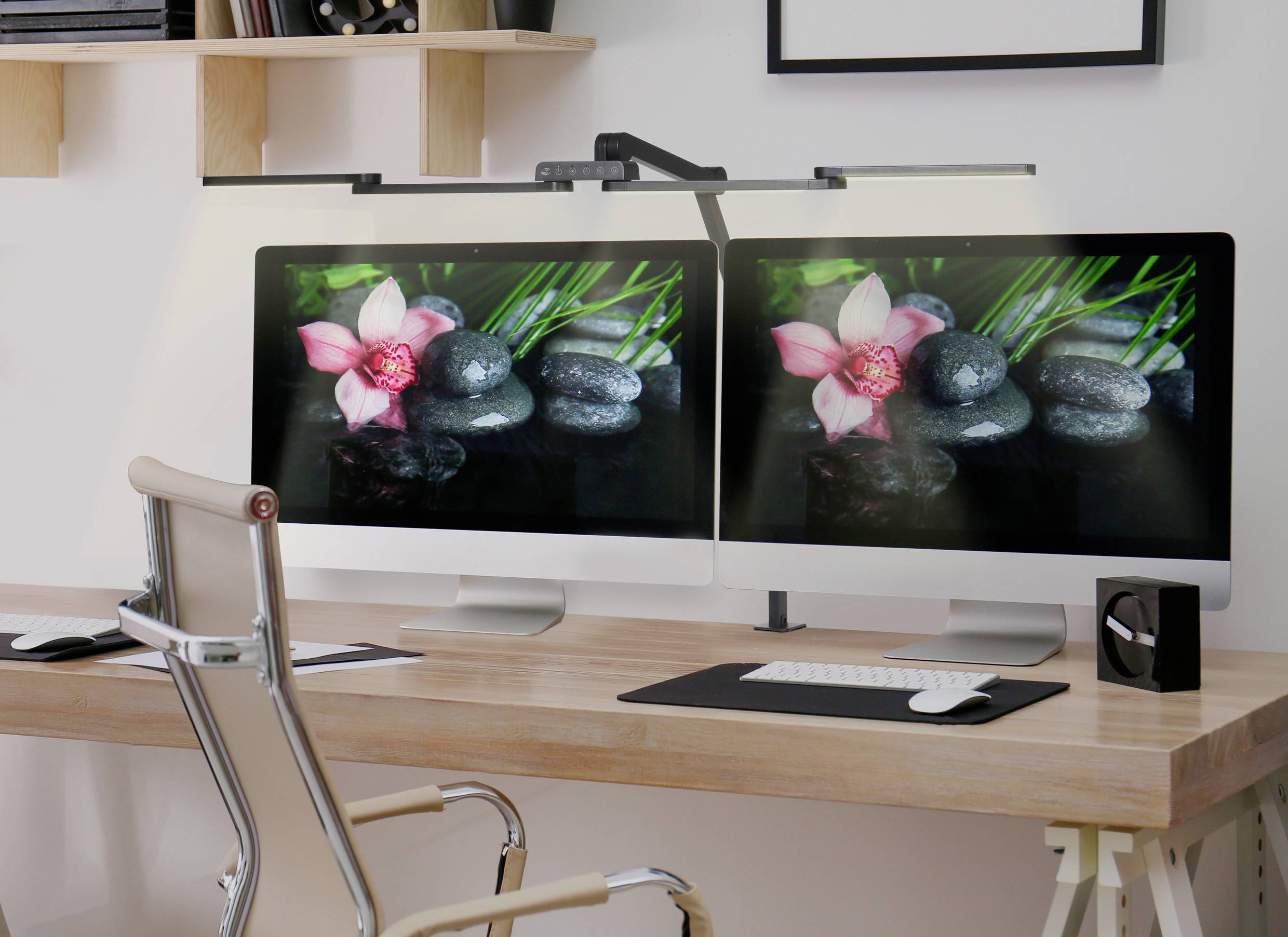 A desk with a computer, whose screen displays an image of stones and flowers. Beside it stands an office chair.