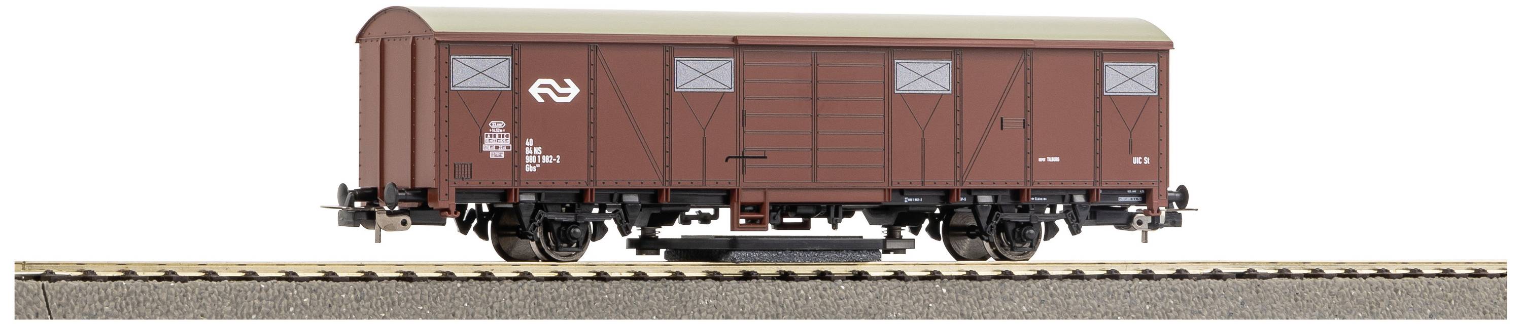 A red goods wagon on a railway track. The wagon is marked with the logo of the Dutch railway and has closed doors.